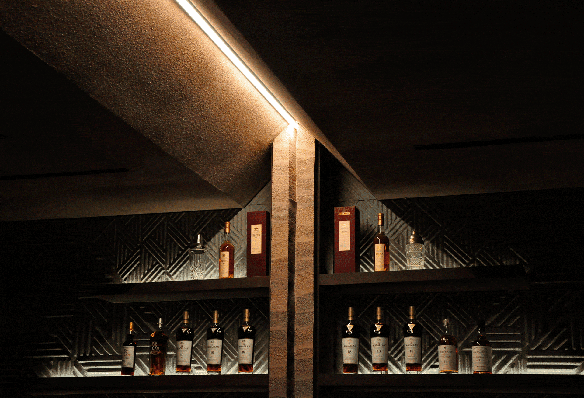 A modern bar shelf display featuring various bottles of whiskey and spirits with a black metallic construction.