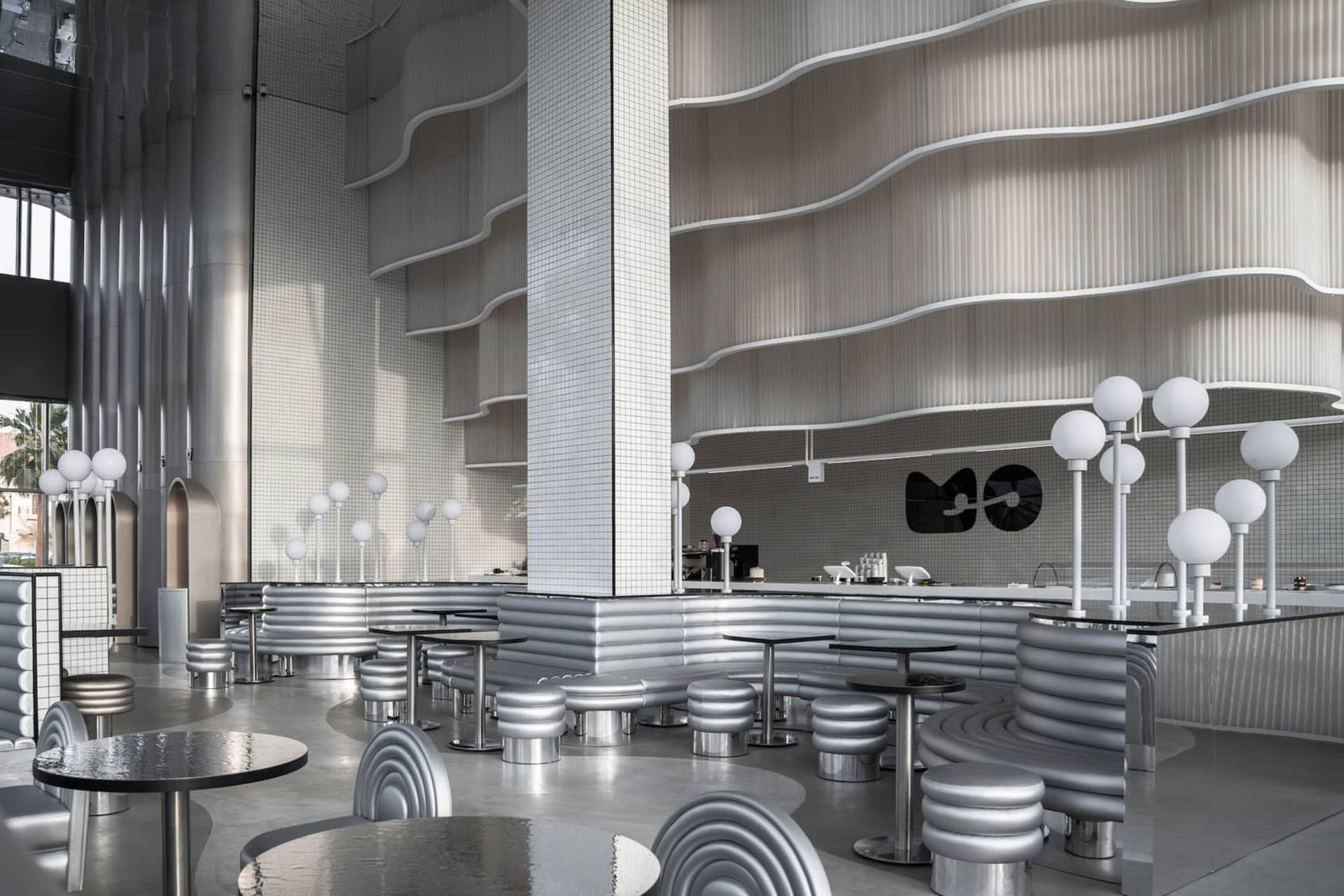 A contemporary metallic bar interior with sleek, curved furniture and a futuristic design aesthetic.