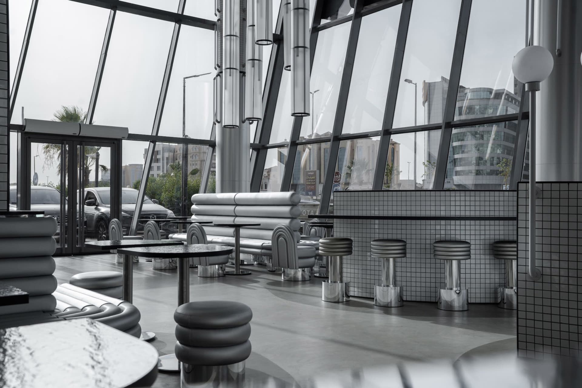 Modern restaurant interior with large glass walls and sleek, contemporary furniture.