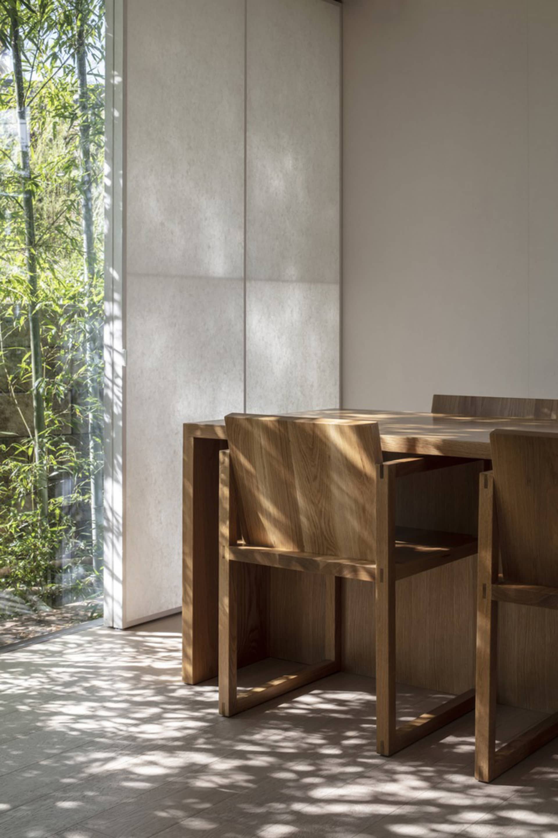 Minimalist interior design featuring a wooden table with a natural light-filled space, showcasing sleek lines and a monochrom
