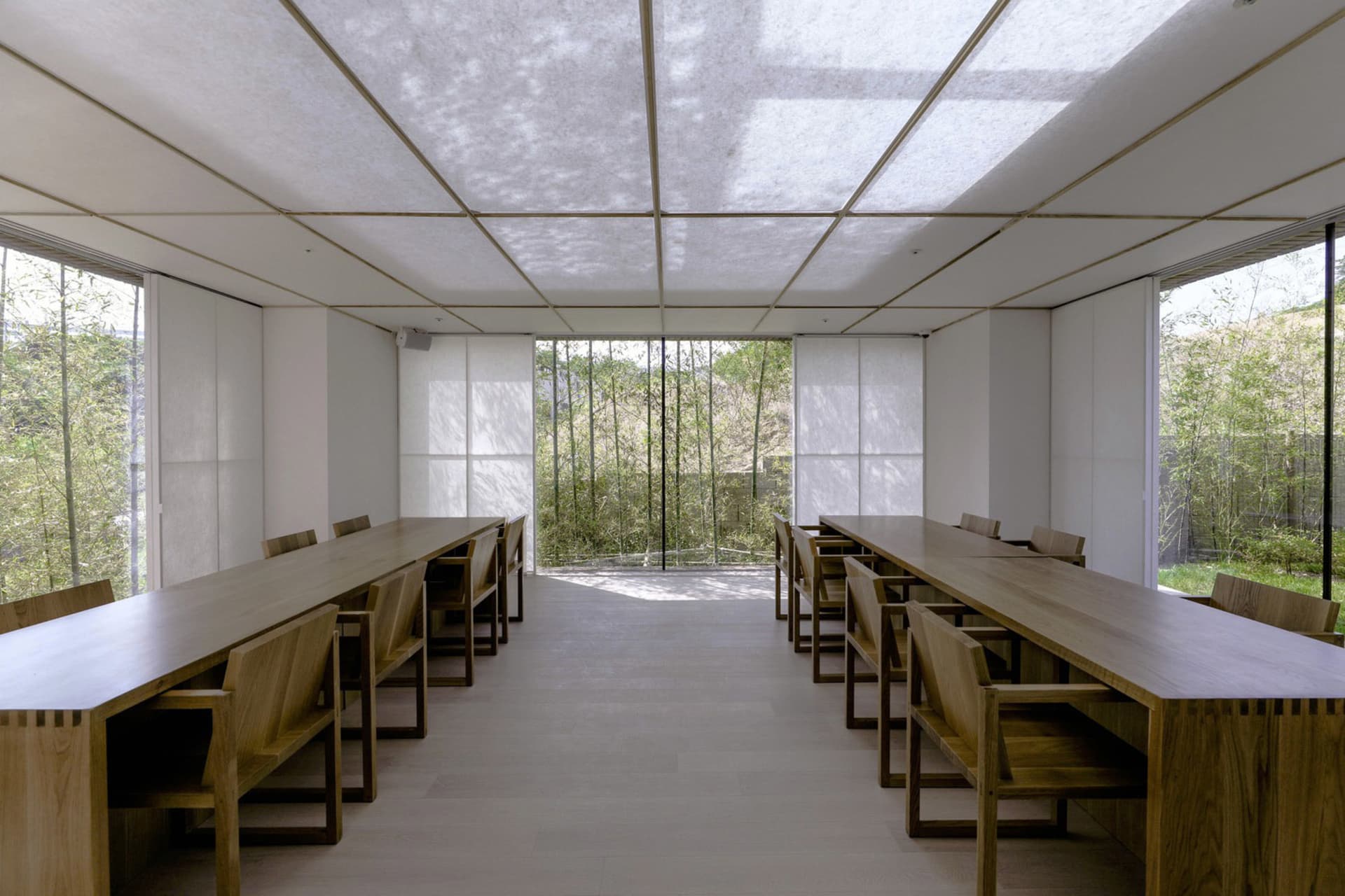 A minimalist workspace with wooden tables and glass walls, featuring a modern design.