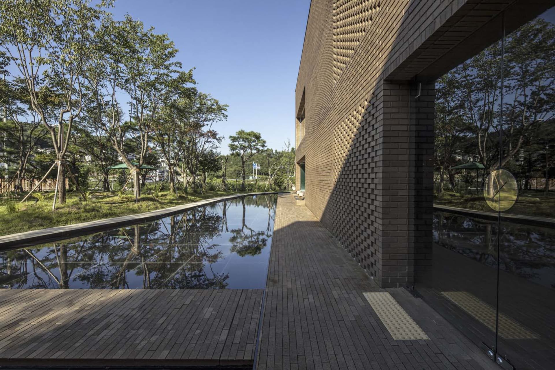 Modern exterior of a pool house featuring brick, glass, and wooden elements.