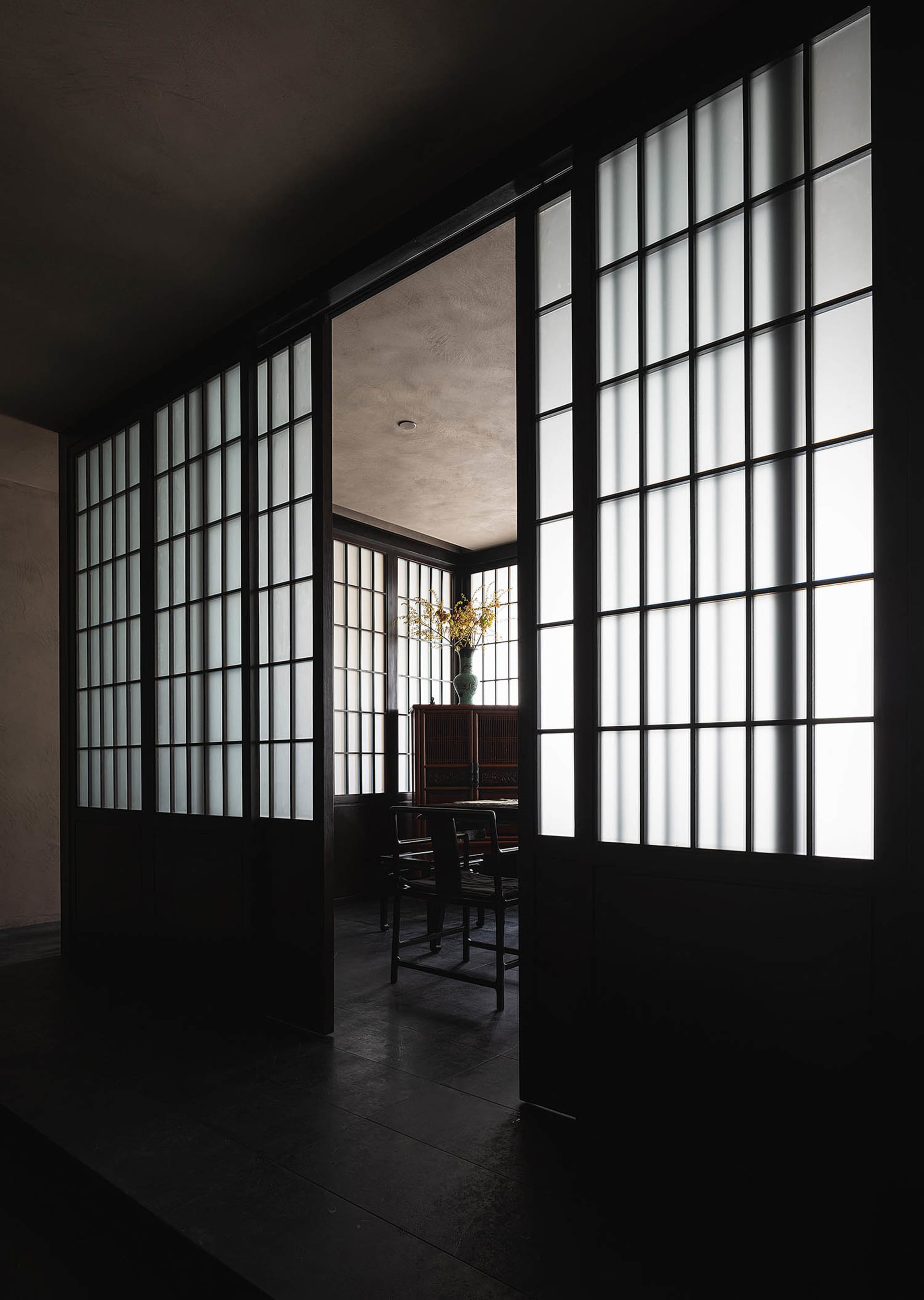 A minimalist room featuring white windows, wooden flooring, and simple furniture.