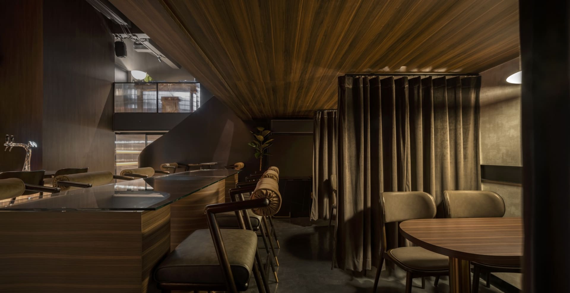 A modern-themed restaurant bar interior with wooden furniture and paneling.