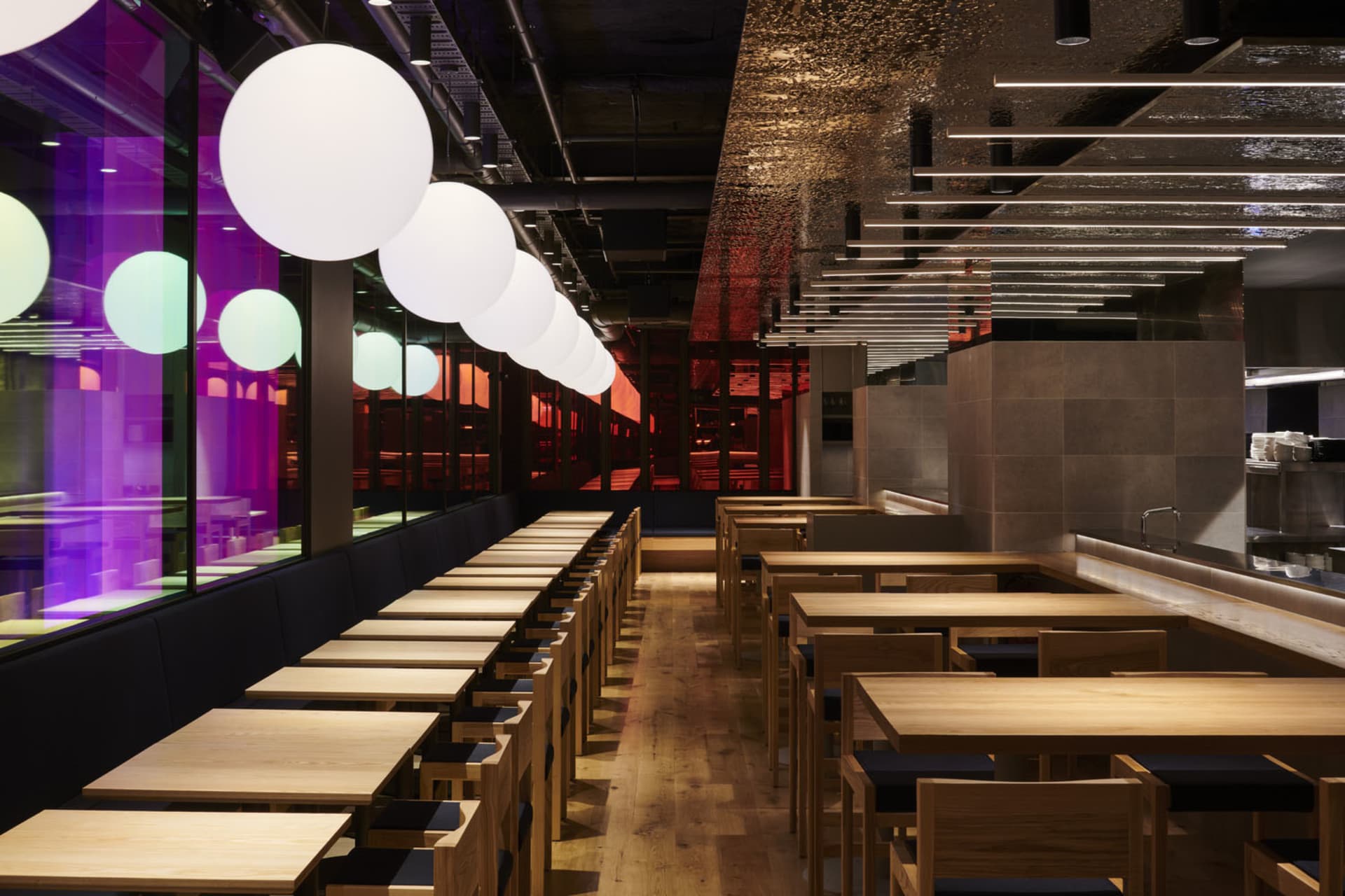 A modern restaurant interior featuring wooden furniture and contemporary lighting design.