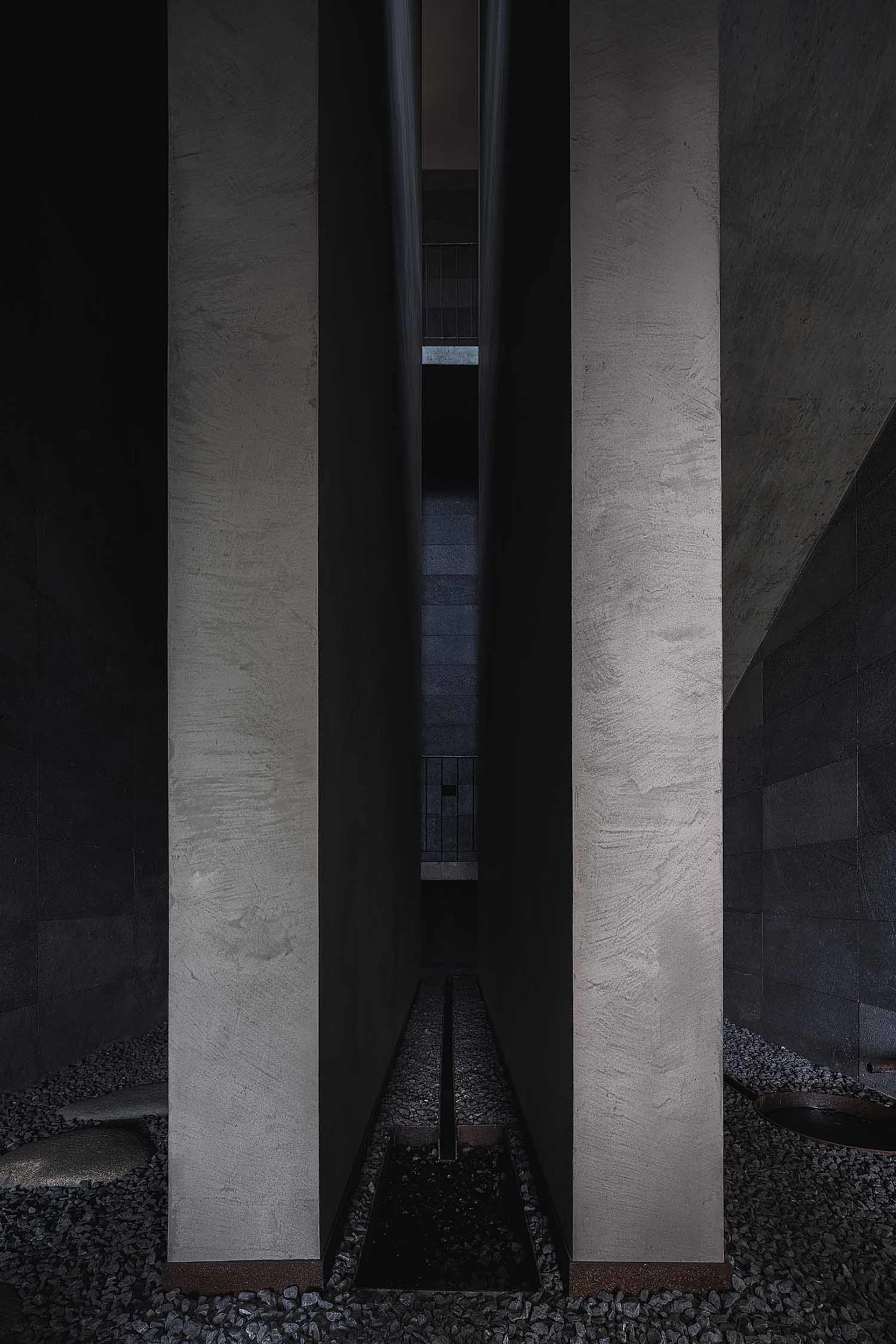 A modern interior space featuring concrete walls and gravel floors.