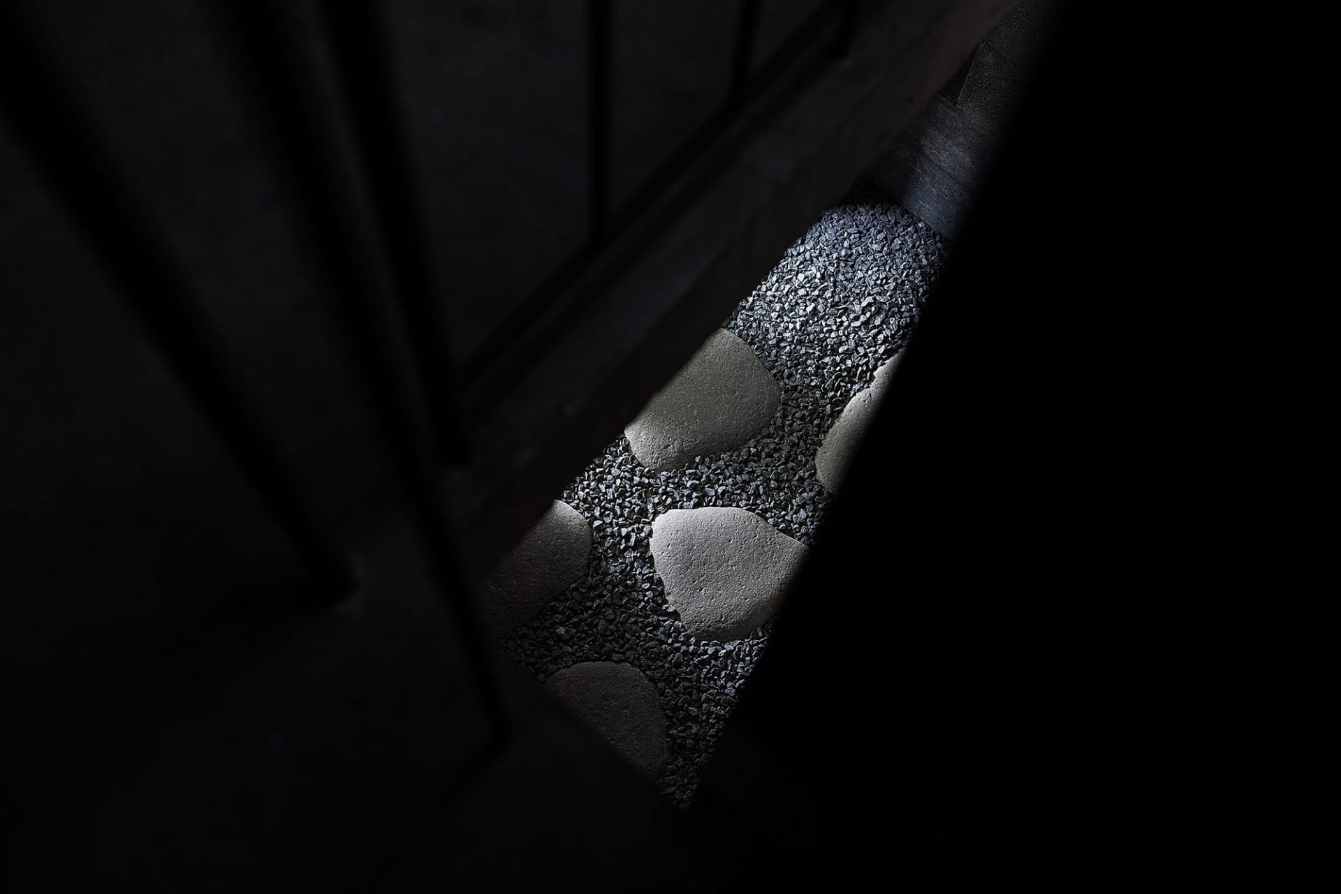A close-up view of a concrete staircase with embedded gravel inserts, focusing on the texture and pattern created by the grav