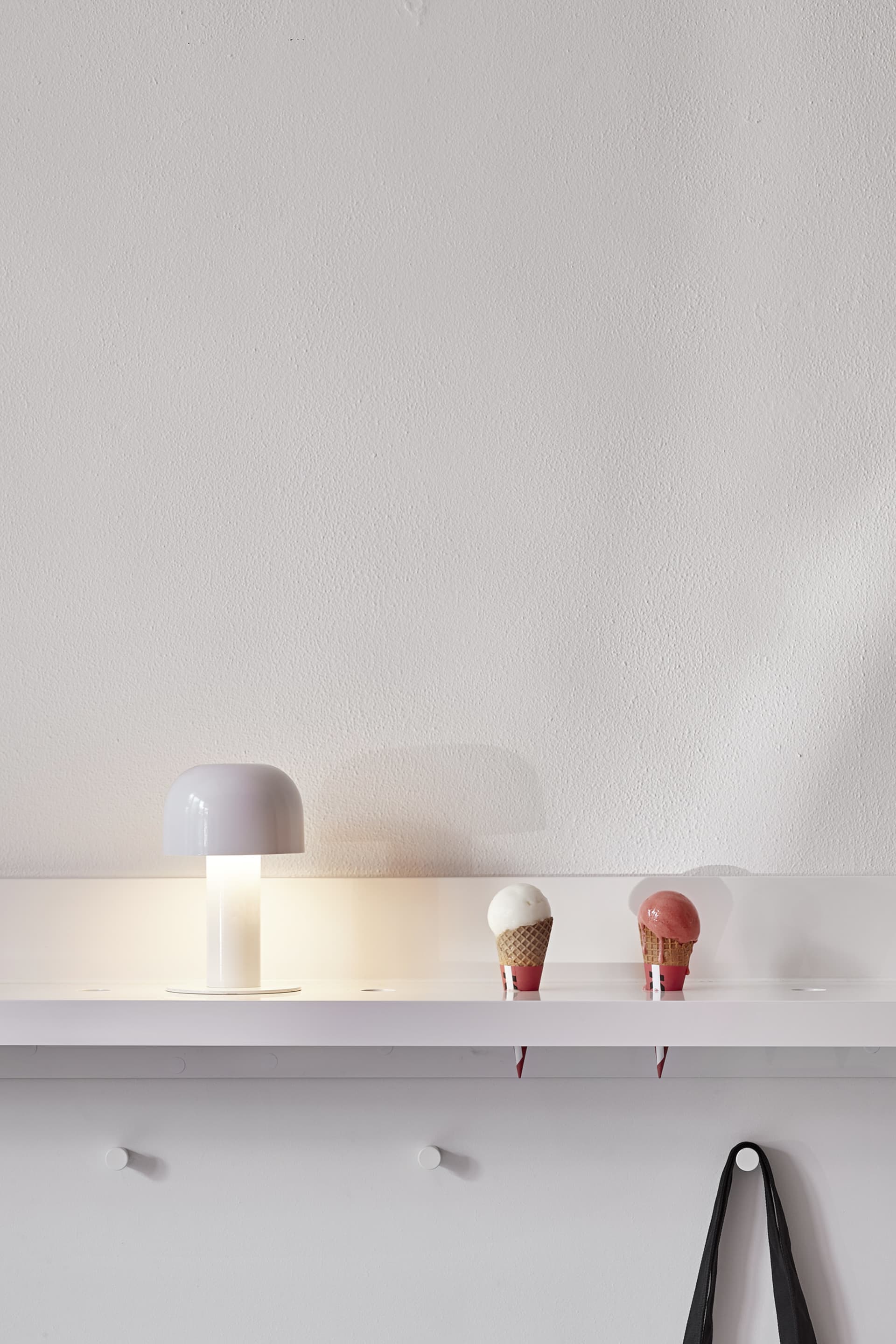 Minimalist white plastic shelf with a white table lamp and ice cream cones.