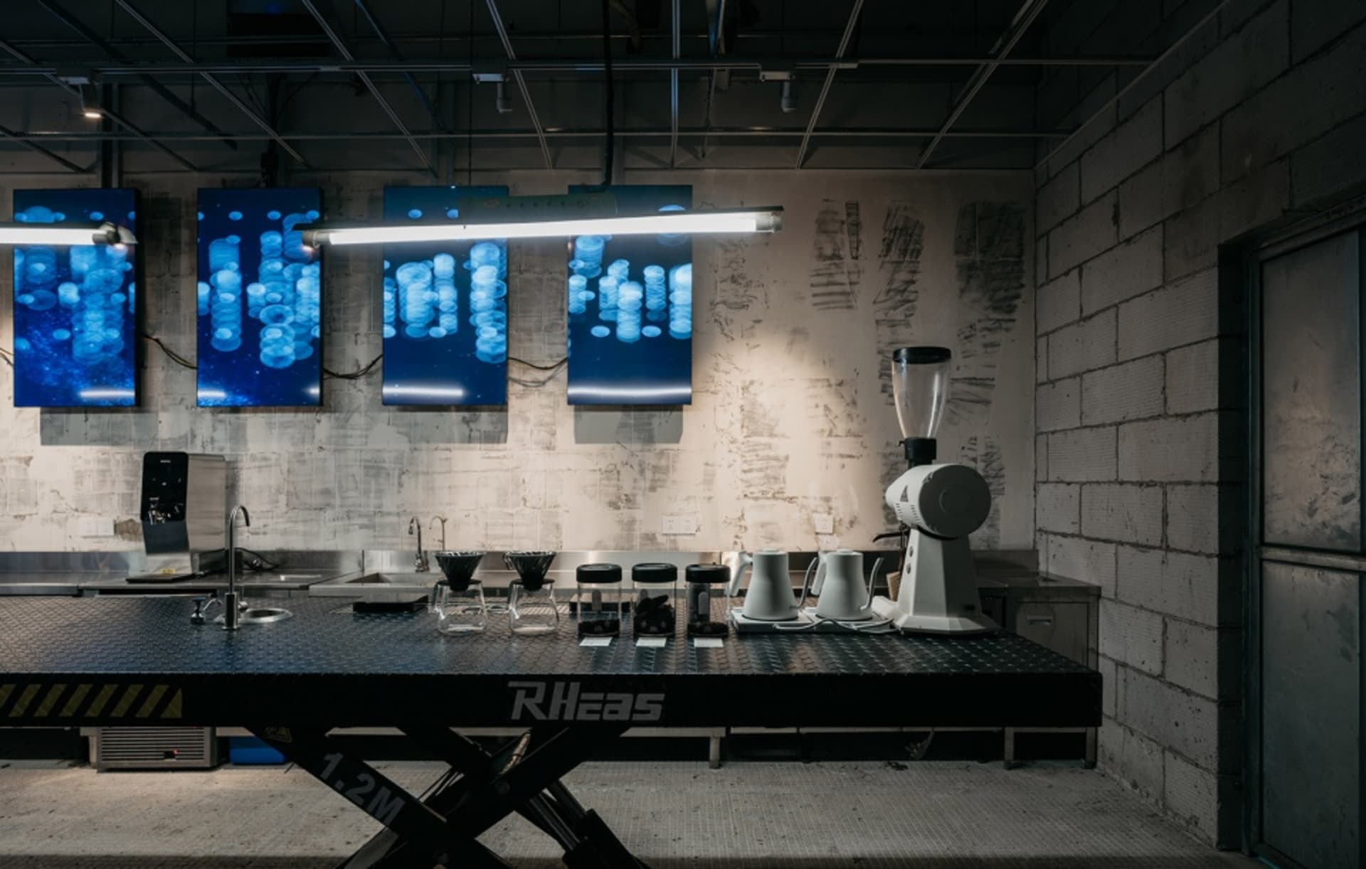 A minimalist coffee shop interior featuring metal and concrete materials.