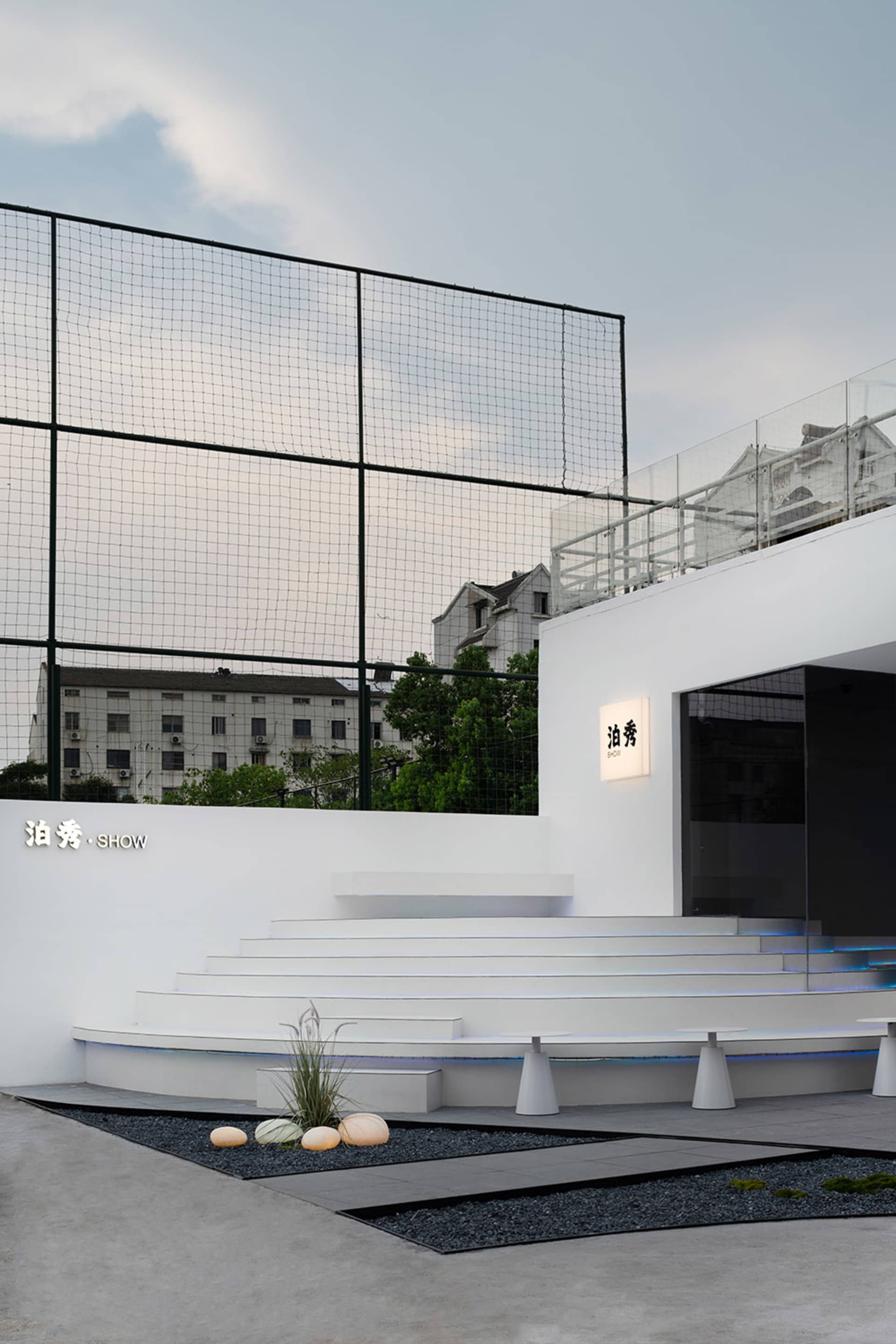 Outdoor modern public space with concrete steps, black gravel, and a black fence.