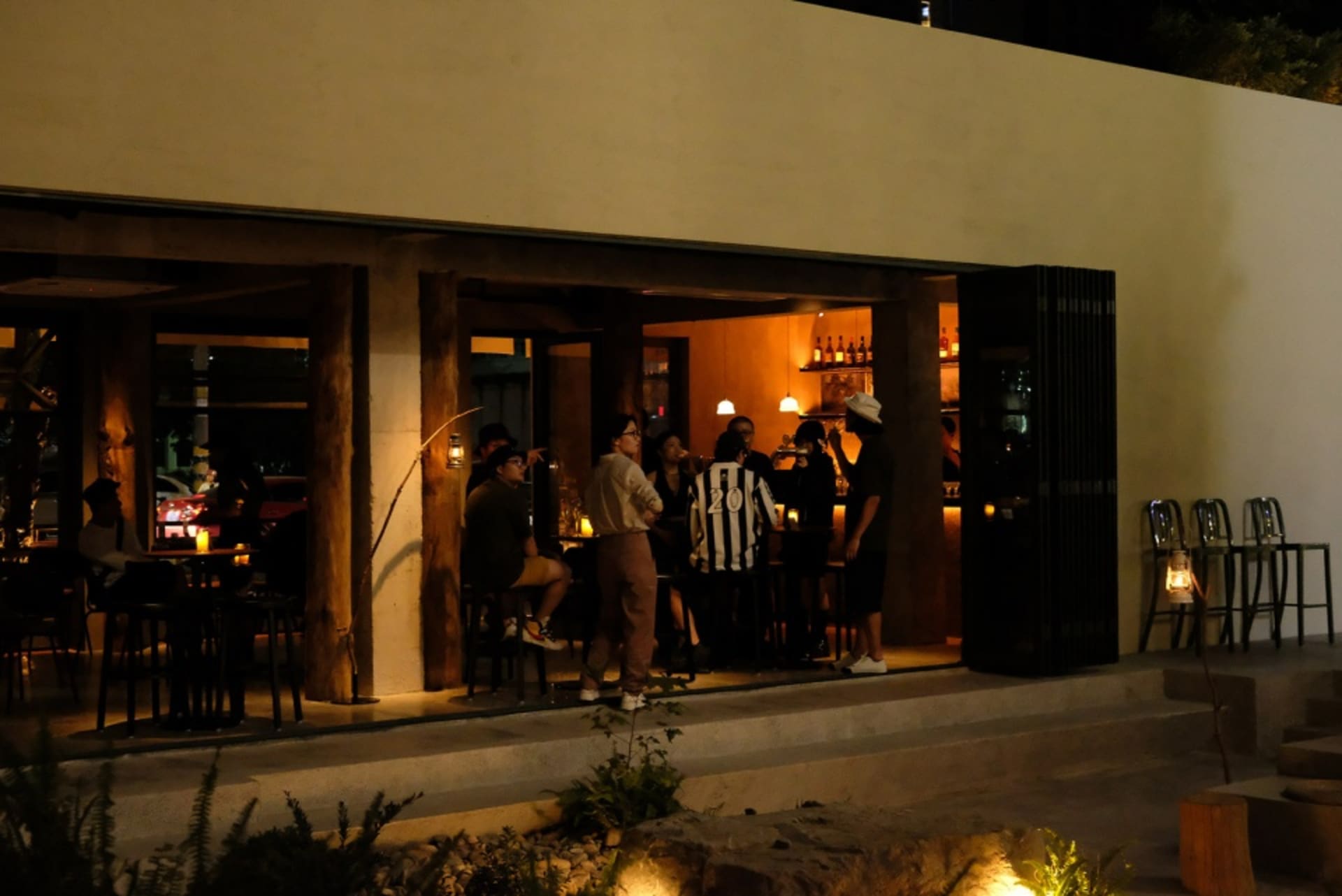 People enjoying drinks in a modern restaurant with concrete and glass elements.
