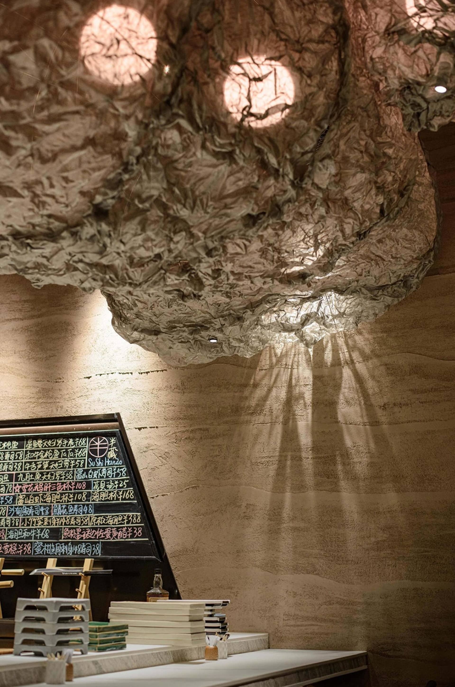 Restaurant interior with a ceiling made of paper-mâché, creating a textured, organic atmosphere.