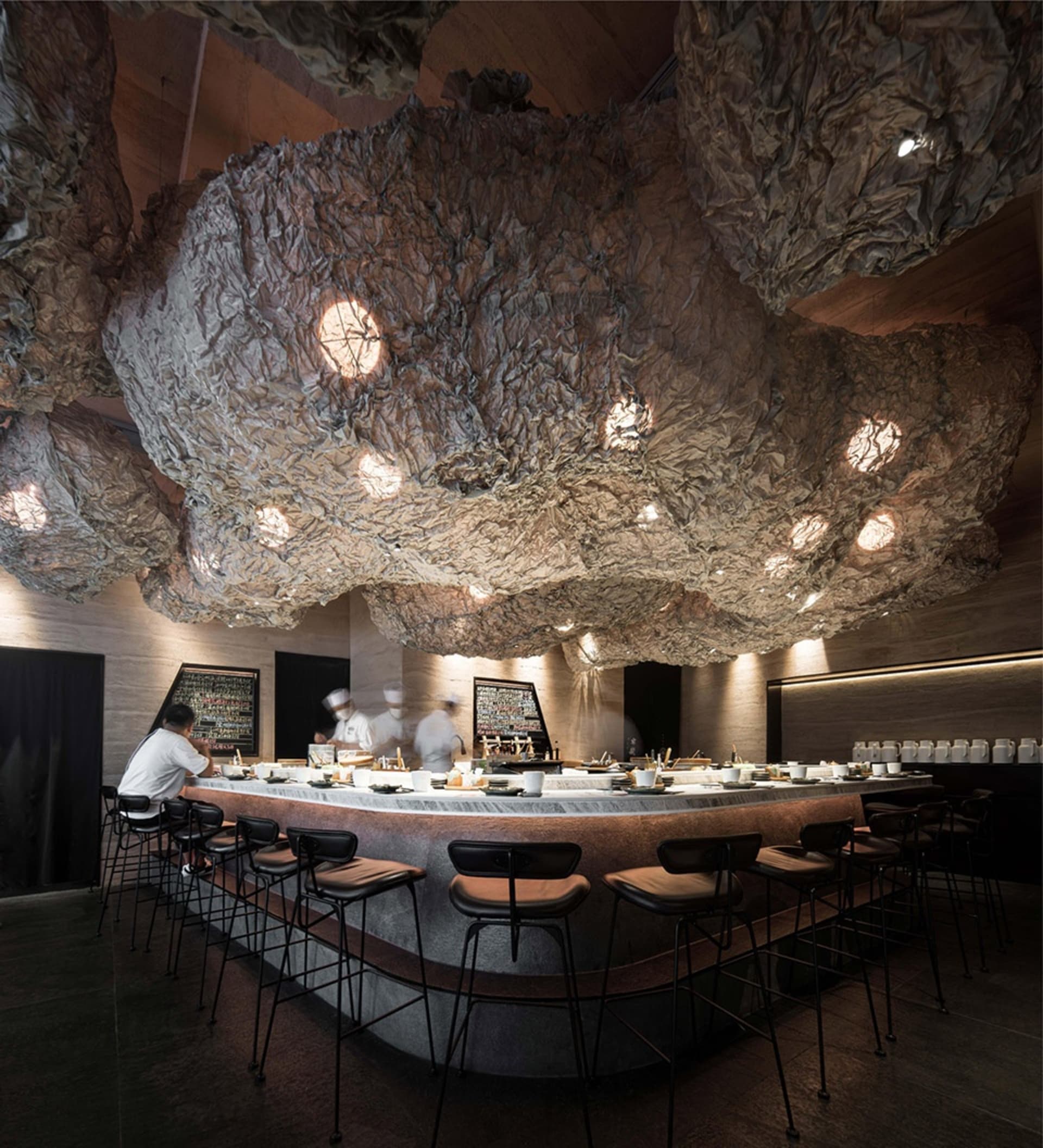 Interior of a modern, industrial-style restaurant featuring concrete and metal materials.