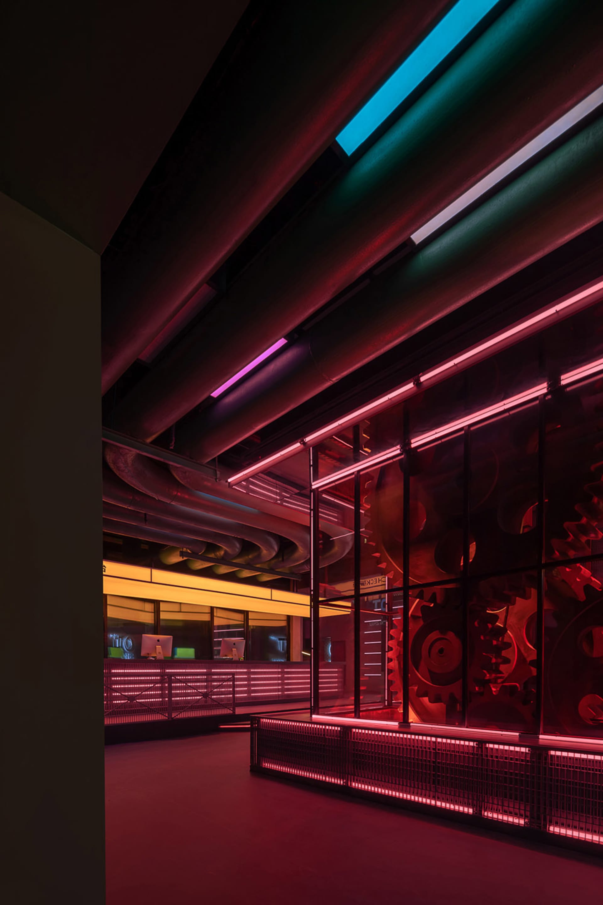 A modern office interior with red neon lights and industrial design elements.