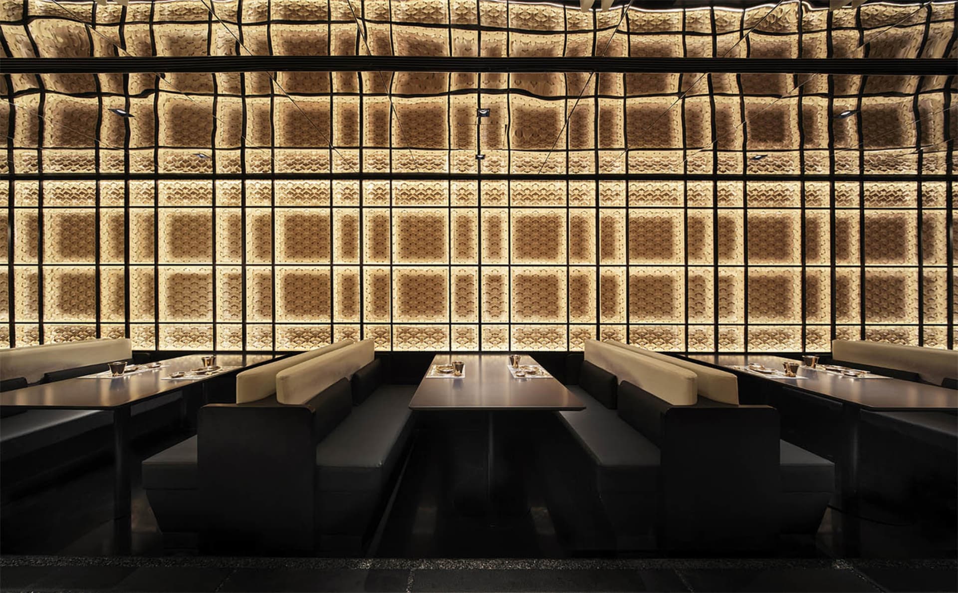 Modern restaurant interior with textured paneled walls and matte black furniture.