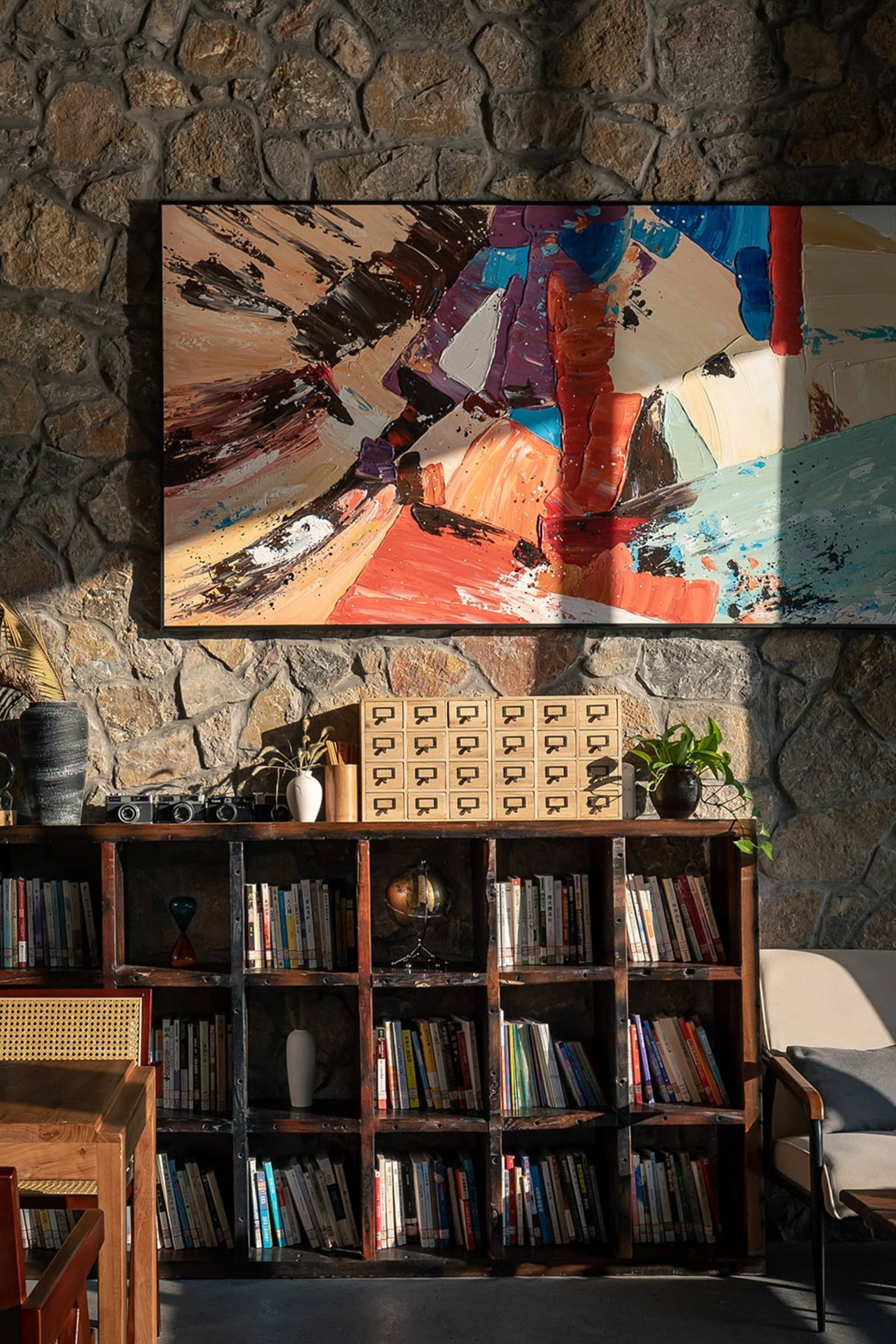 A modern industrial home library with wooden shelves filled with books, a globe, and decorative items.
