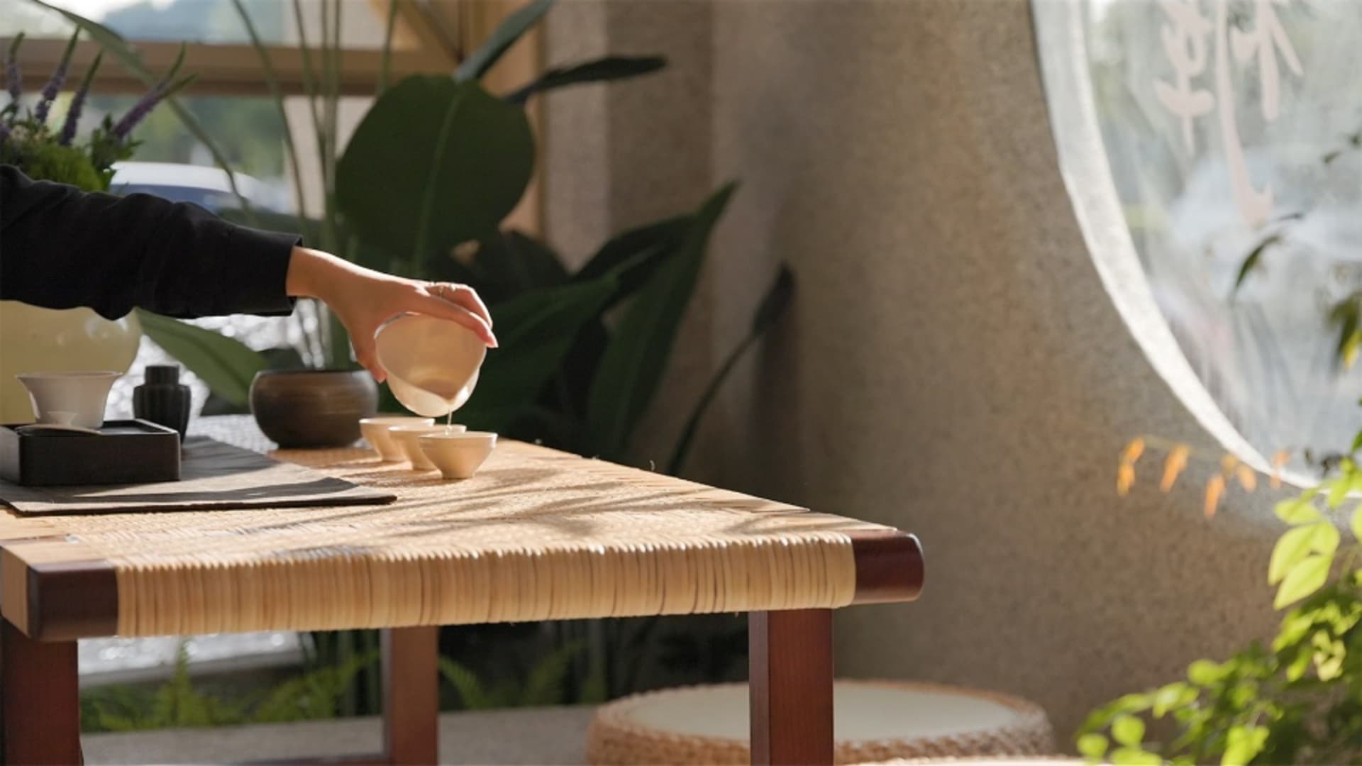 Traditional interior with wooden cane furniture, including a table with bowls and plants in the background.
