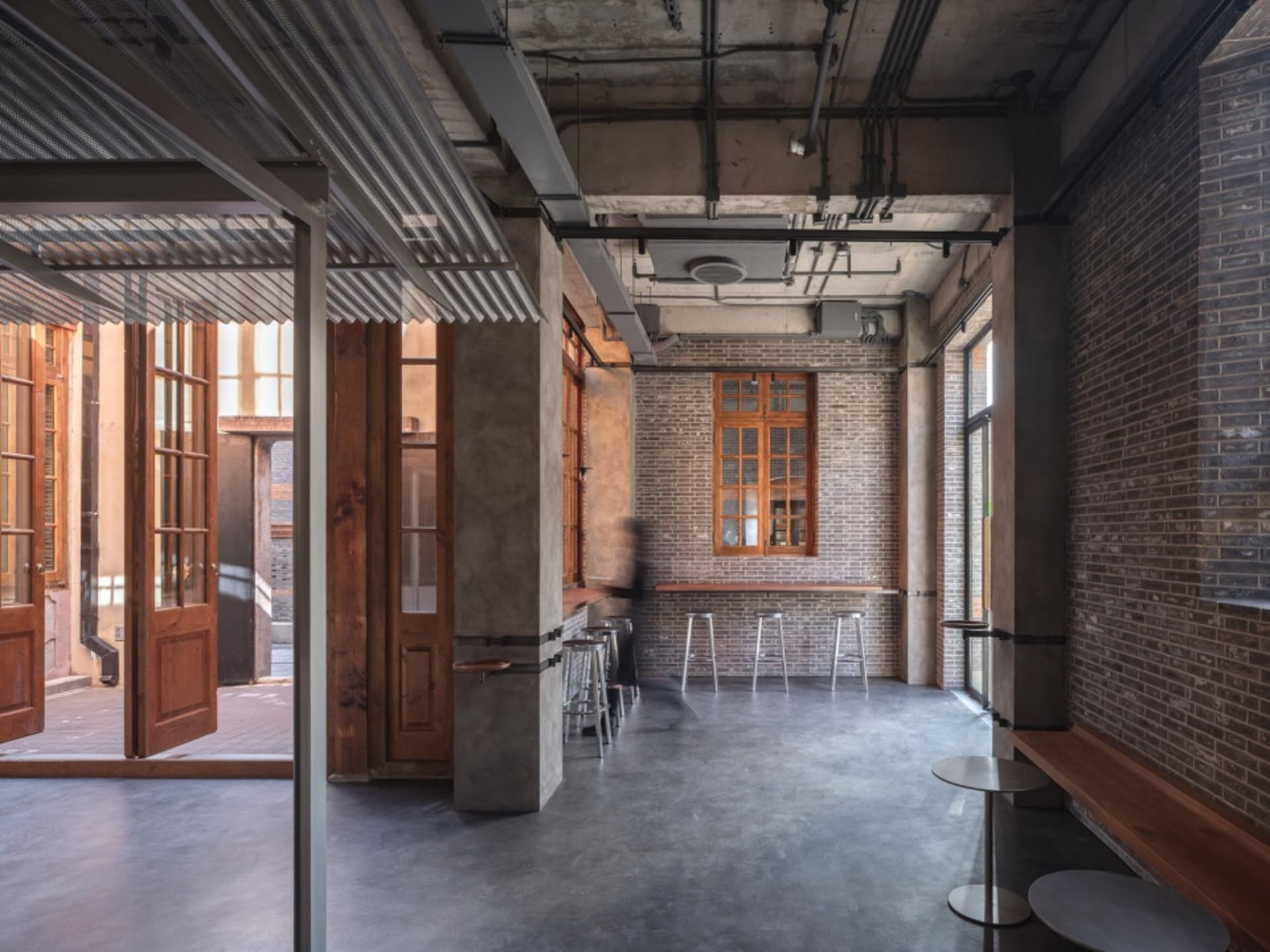 Industrial design bar with concrete flooring, brick walls, and wooden furniture.
