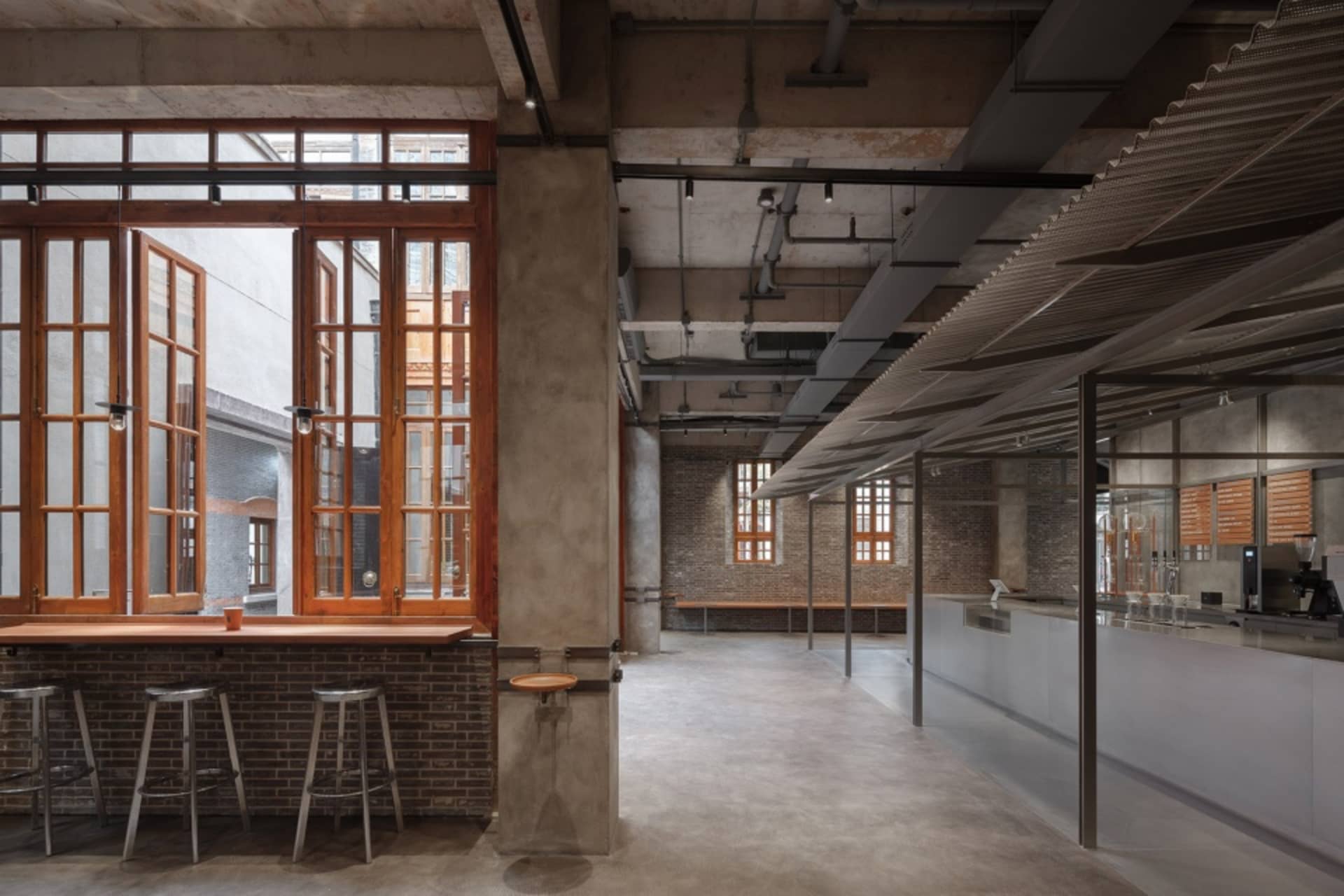 Industrial-style coffee shop interior with brick walls, concrete floors, and metal accents