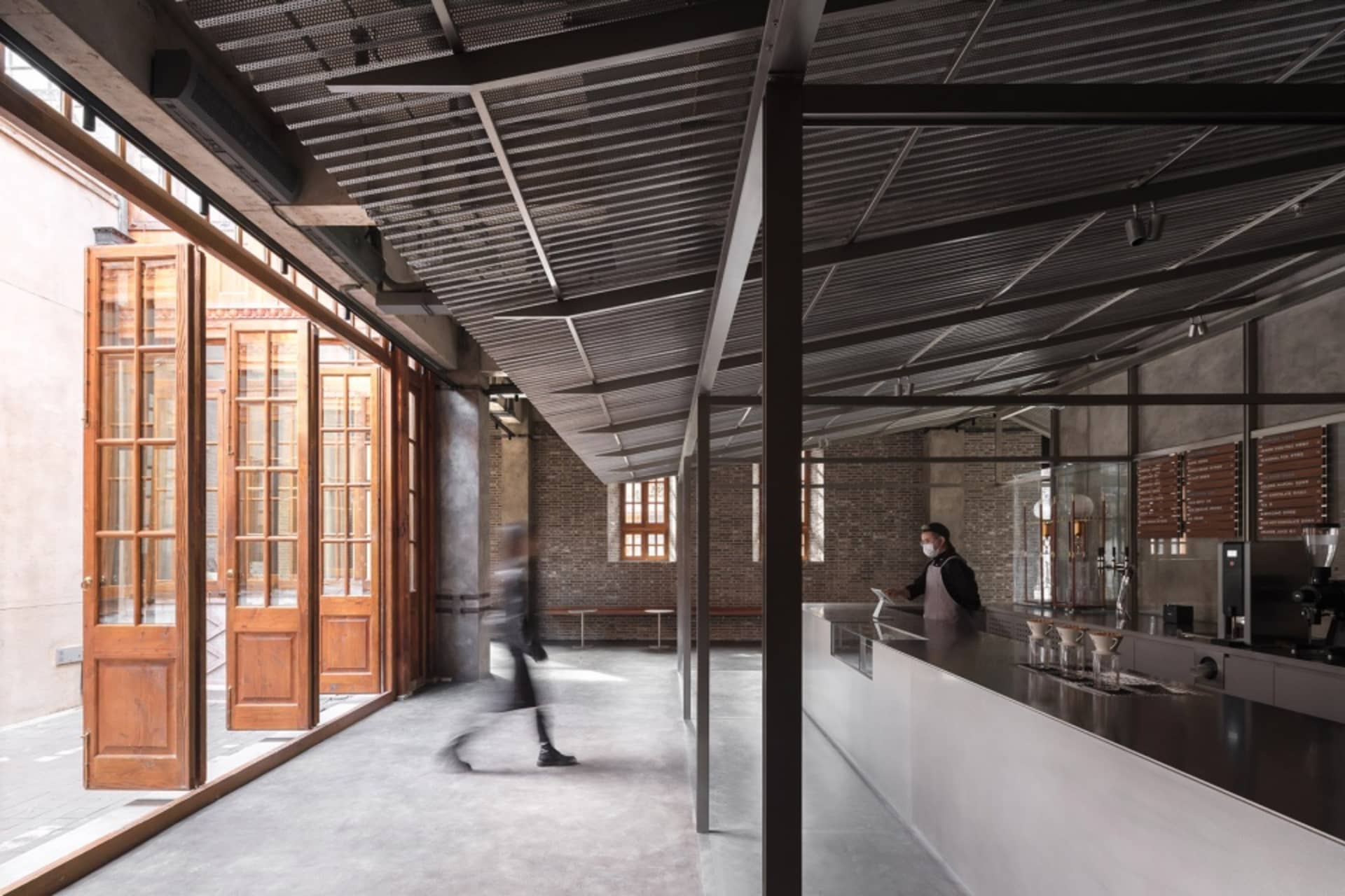 Industrial-style coffee shop with concrete and brick accents, featuring a sleek coffee bar counter.