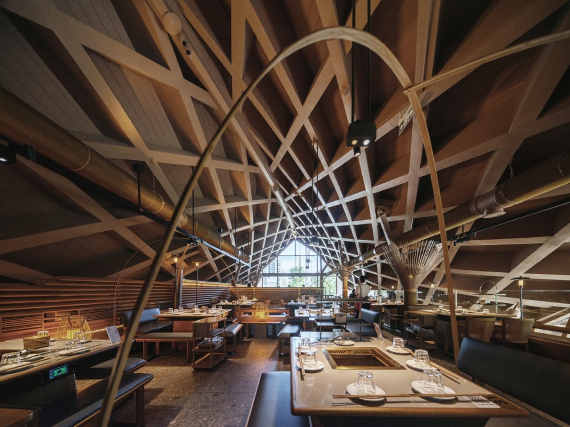 Interior view of an industrial-themed restaurant with wooden elements and geometric ceiling design.