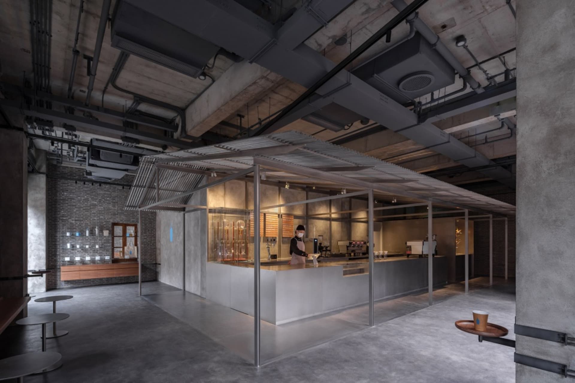 現代工業風咖啡店採用極簡設計,中央設有混凝土吧台與金屬板材。