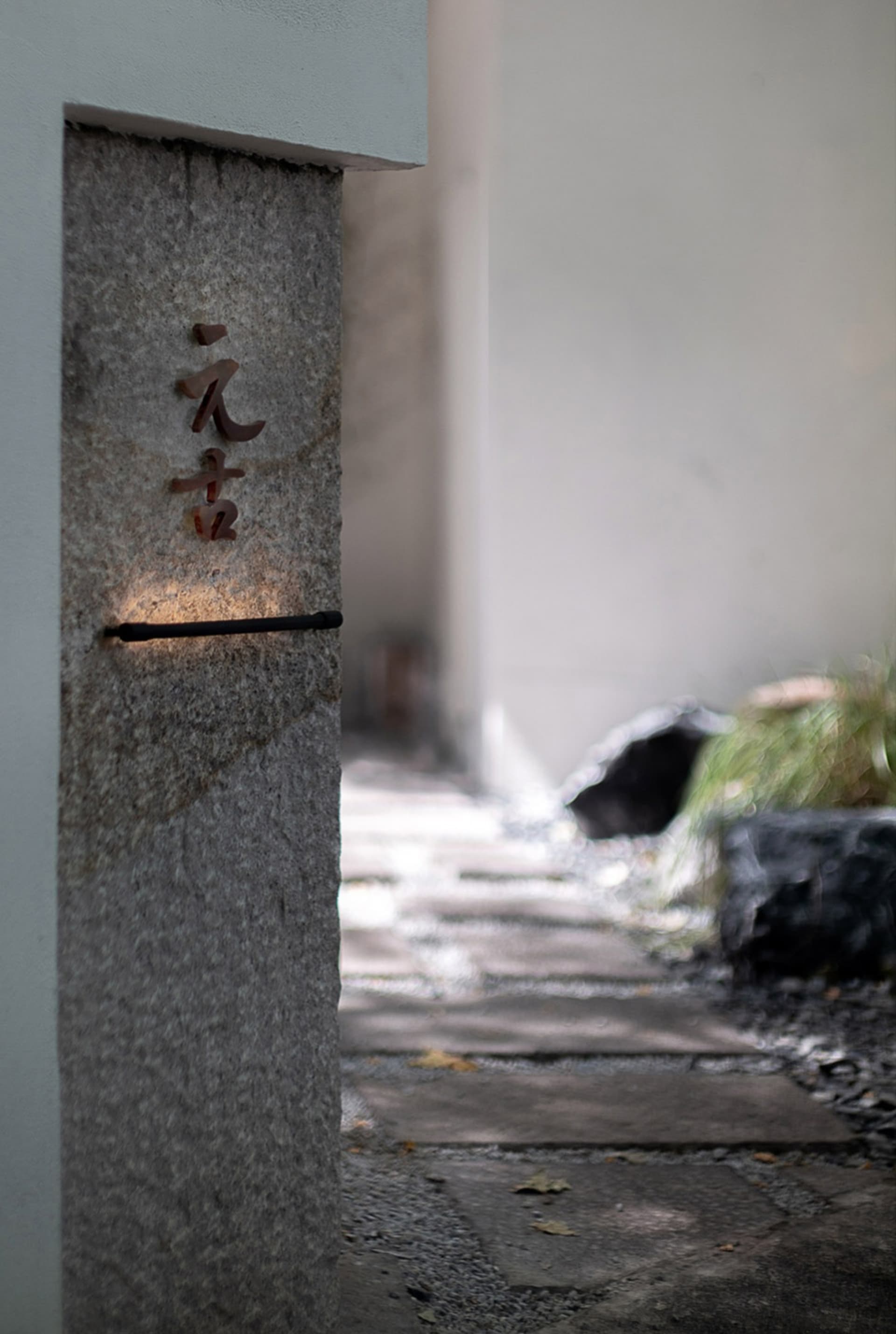 極簡風格的入口招牌，由花崗岩製成，上面刻有日文字符。