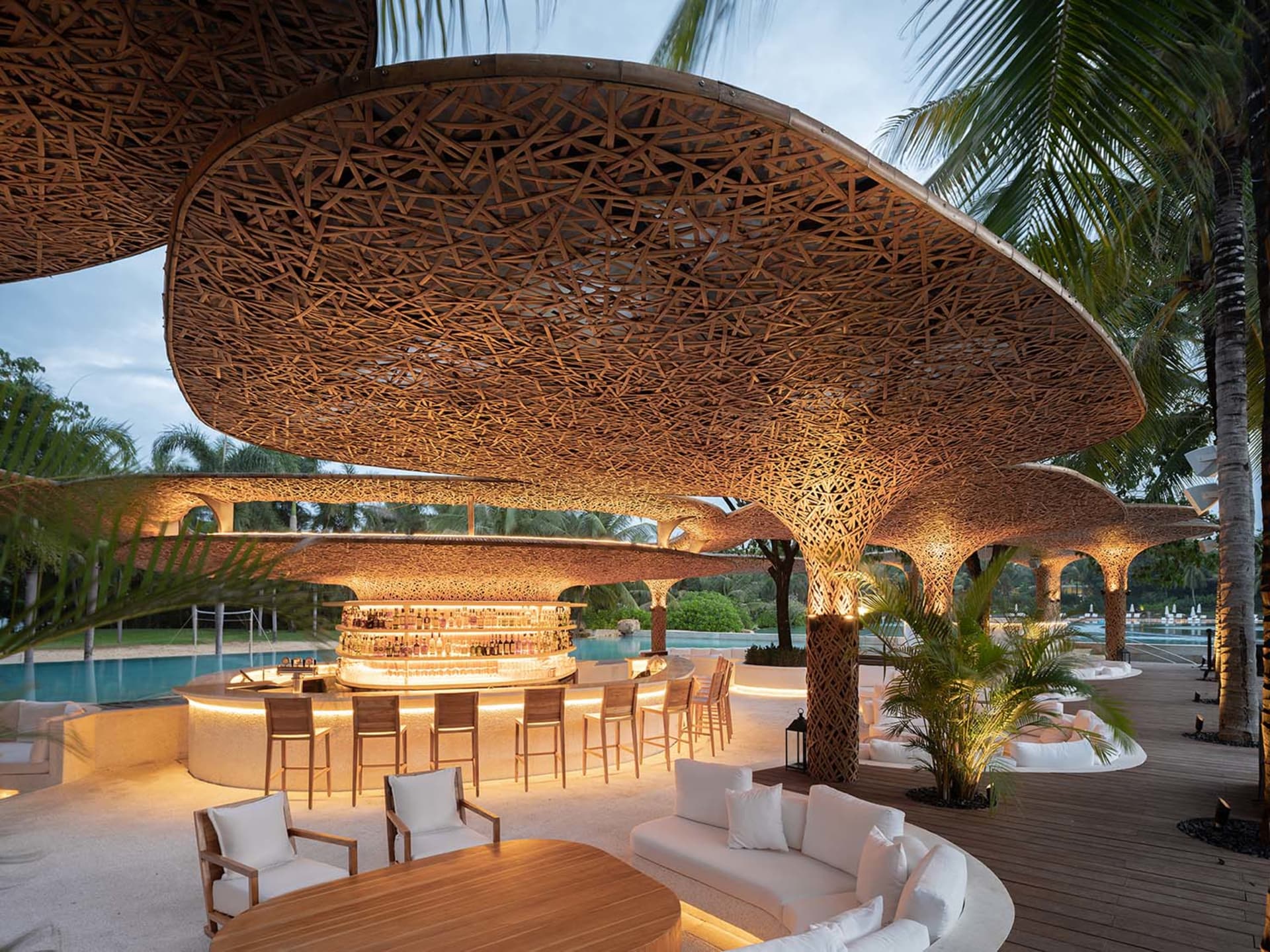 A stylish, modern bar with a wooden roof and seating area next to a pool.