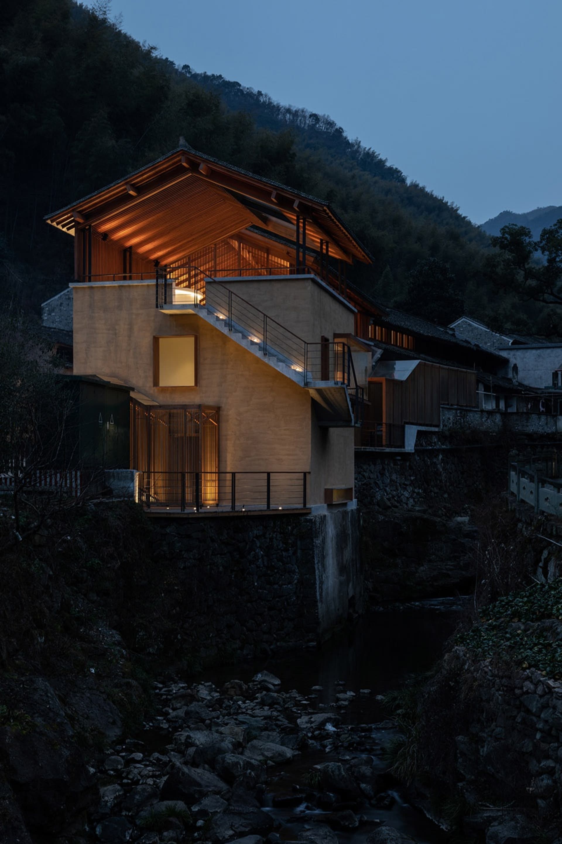 一座現代住宅,融合混凝土與木質元素,黃昏時分,背景為山景。