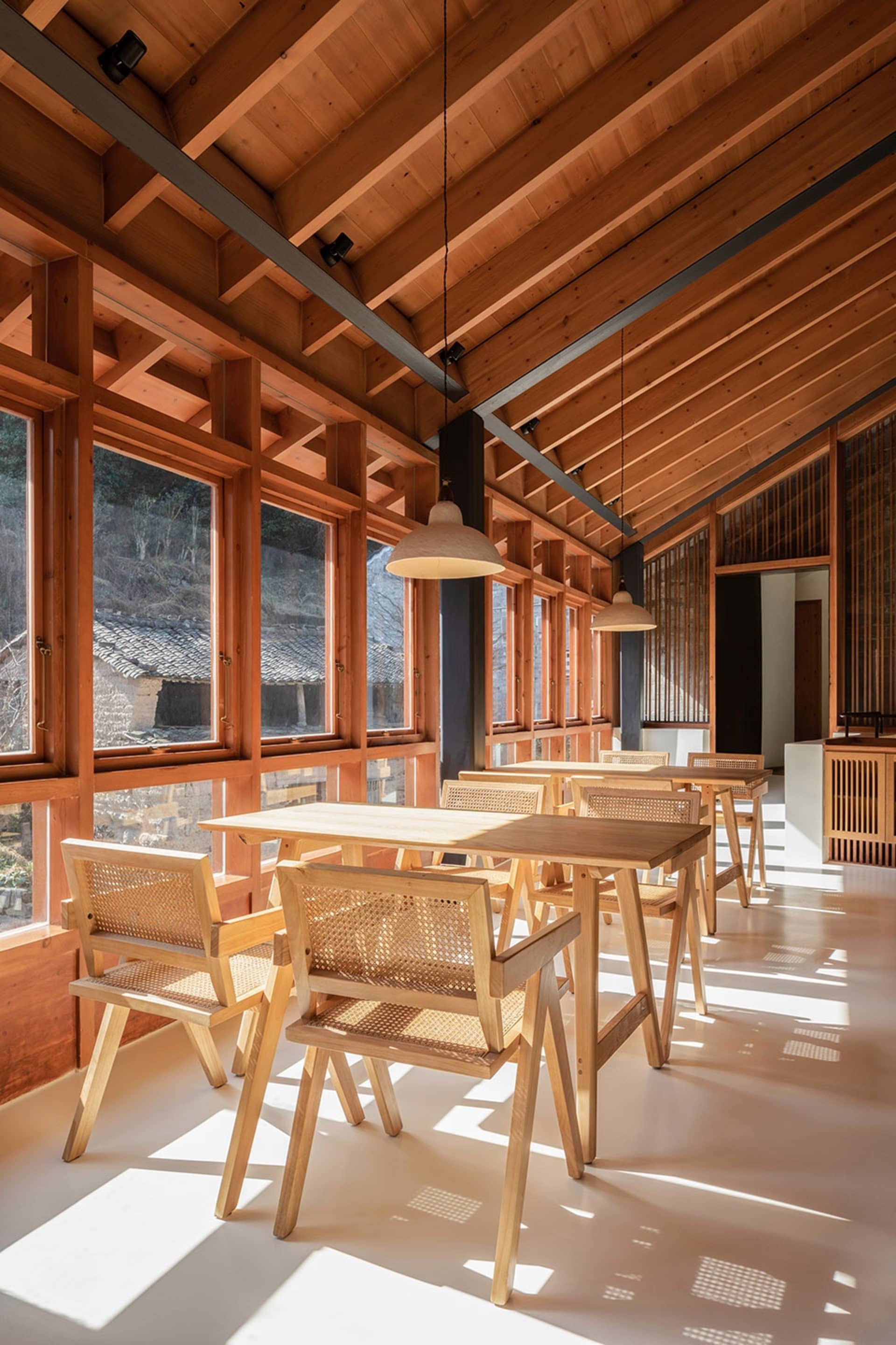 現代餐廳室內空間,擺放木質餐桌與餐椅,大型窗戶引入自然光線。