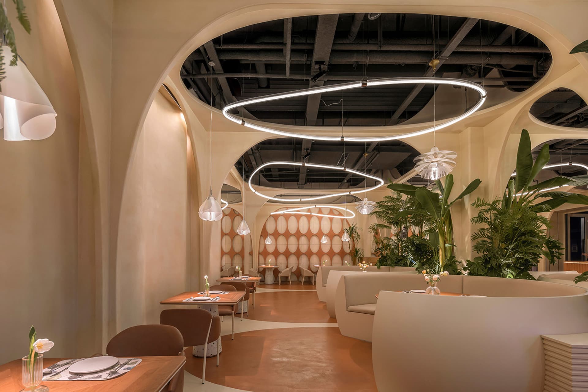 A modern restaurant interior with neutral-colored decor and arch-shaped ceiling lights.