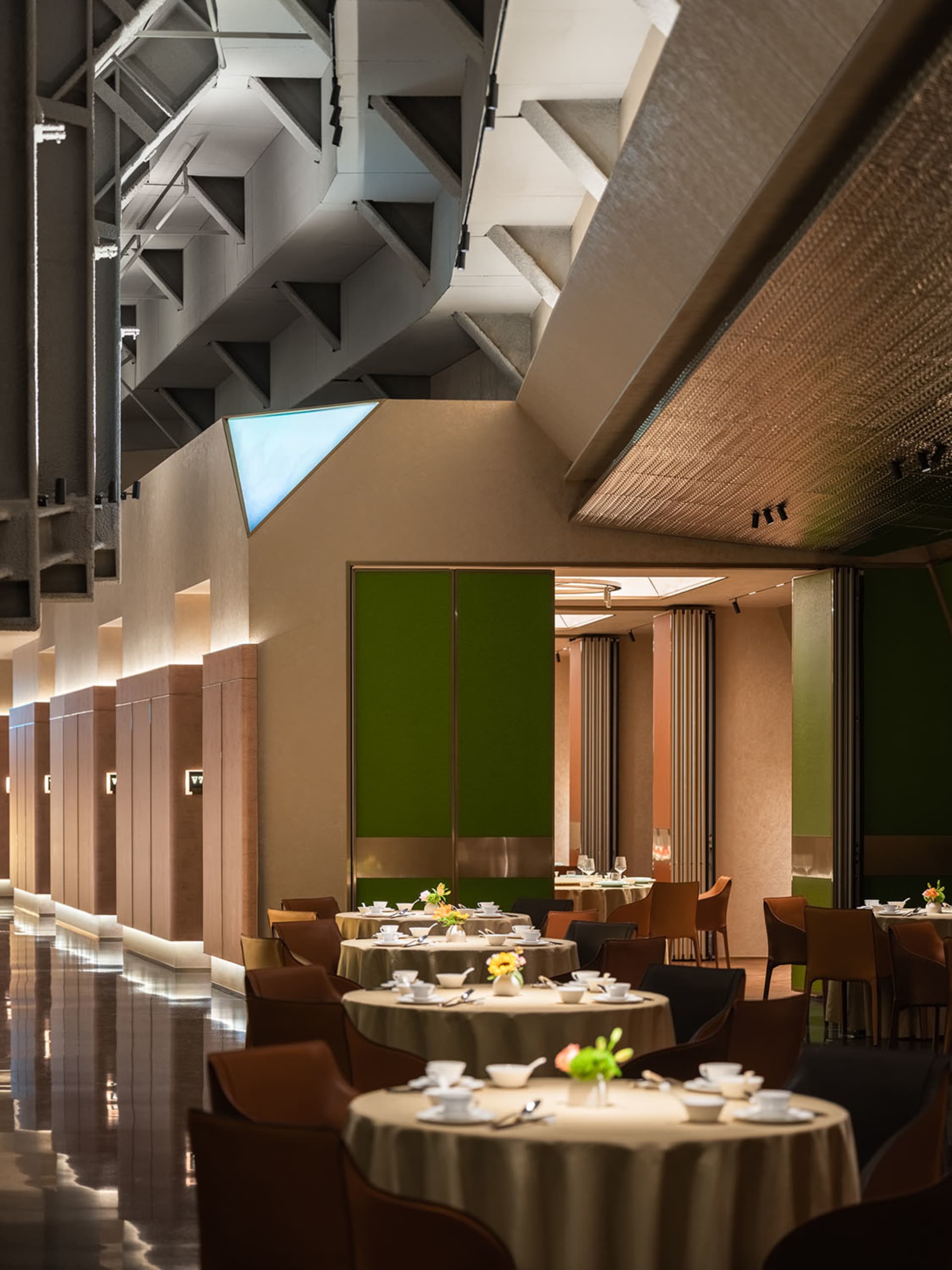 Modern restaurant interior with metal columns, glass walls, and fabric partitioning.