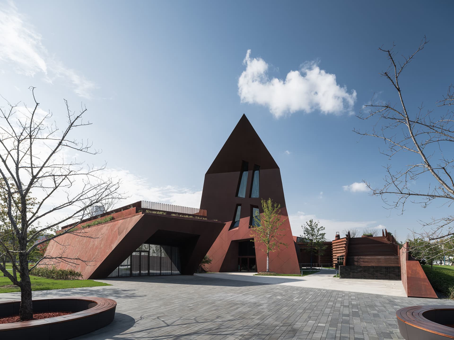 A modern, geometric building with a metallic exterior featuring large windows and a pointed roof.