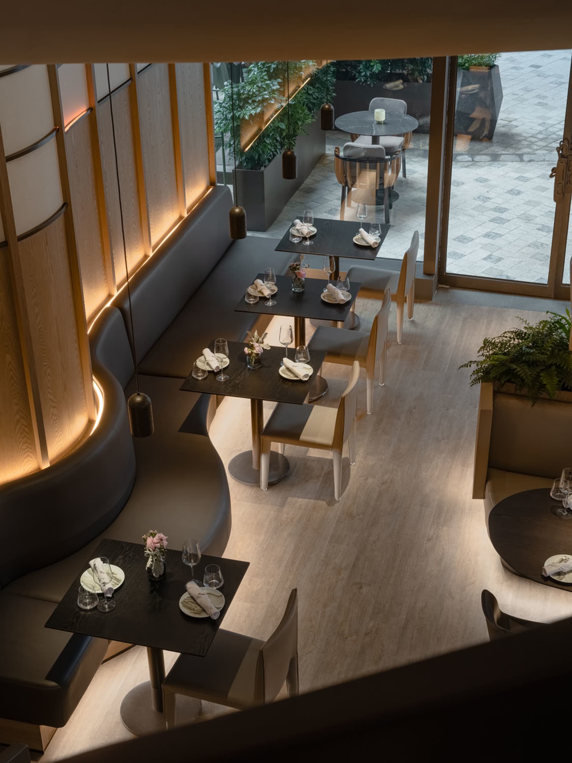 Modern restaurant interior with black tables, white chairs, and wooden flooring.