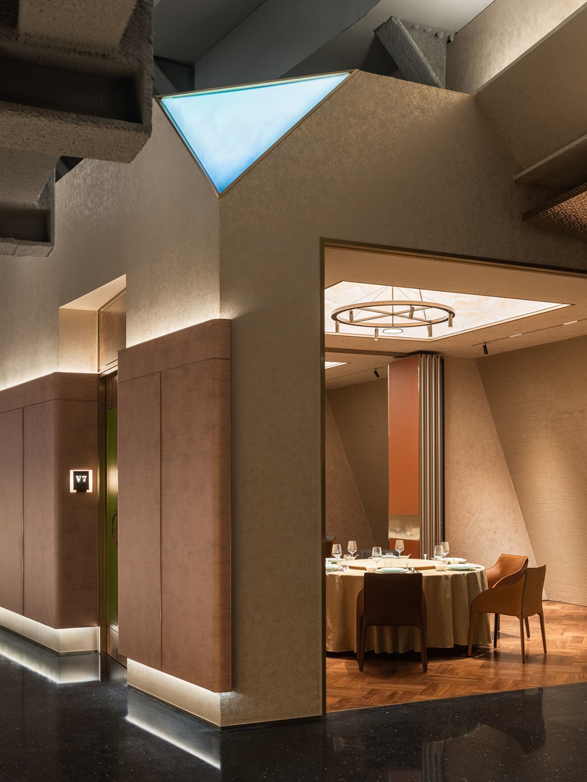 Modern restaurant dining room with concrete columns, exposed beams, and a circular light fixture