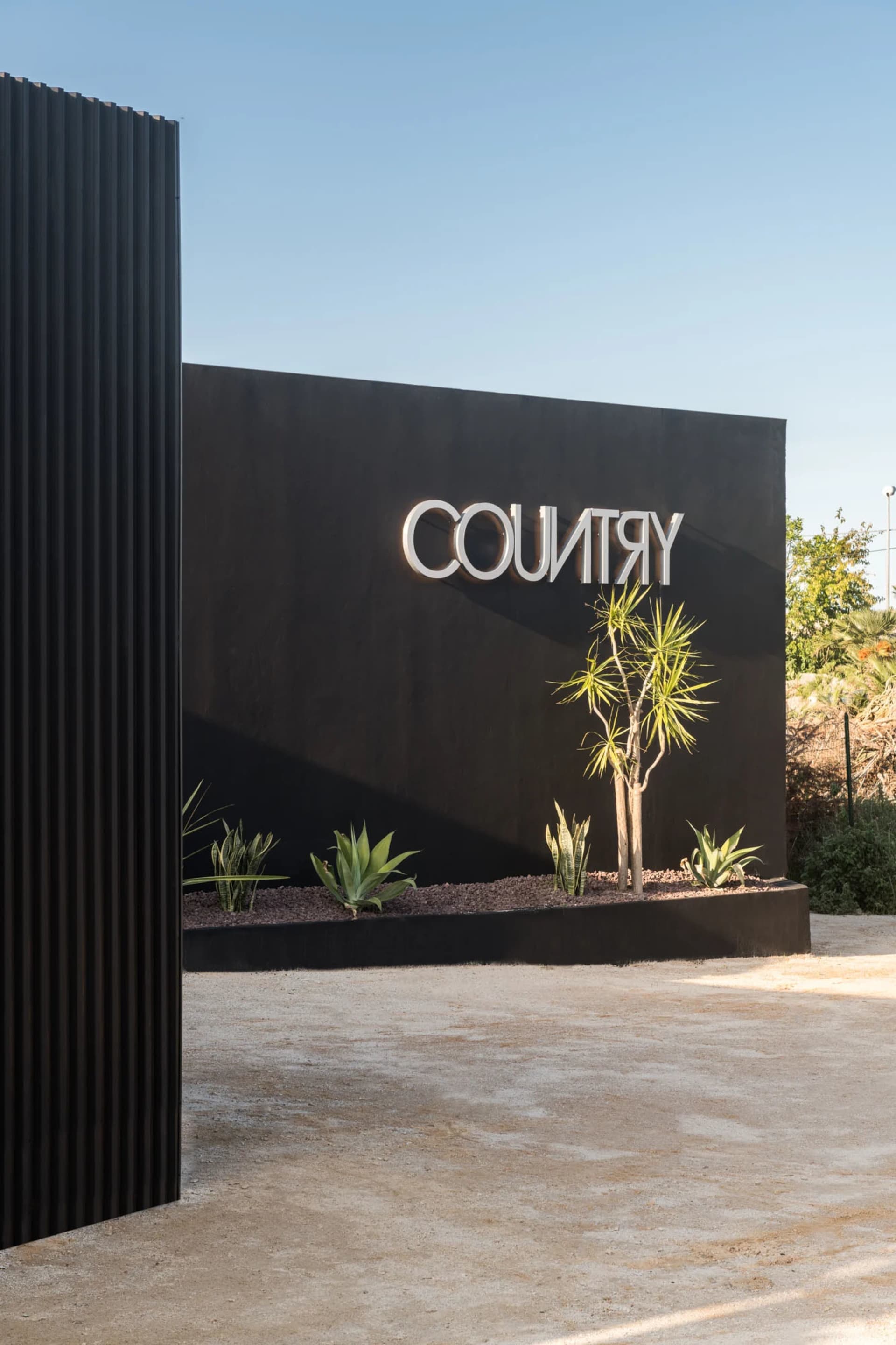辦公室入口處的黑牆上掛有現代風格的「COUNTRY」招牌,地面為混凝土材質