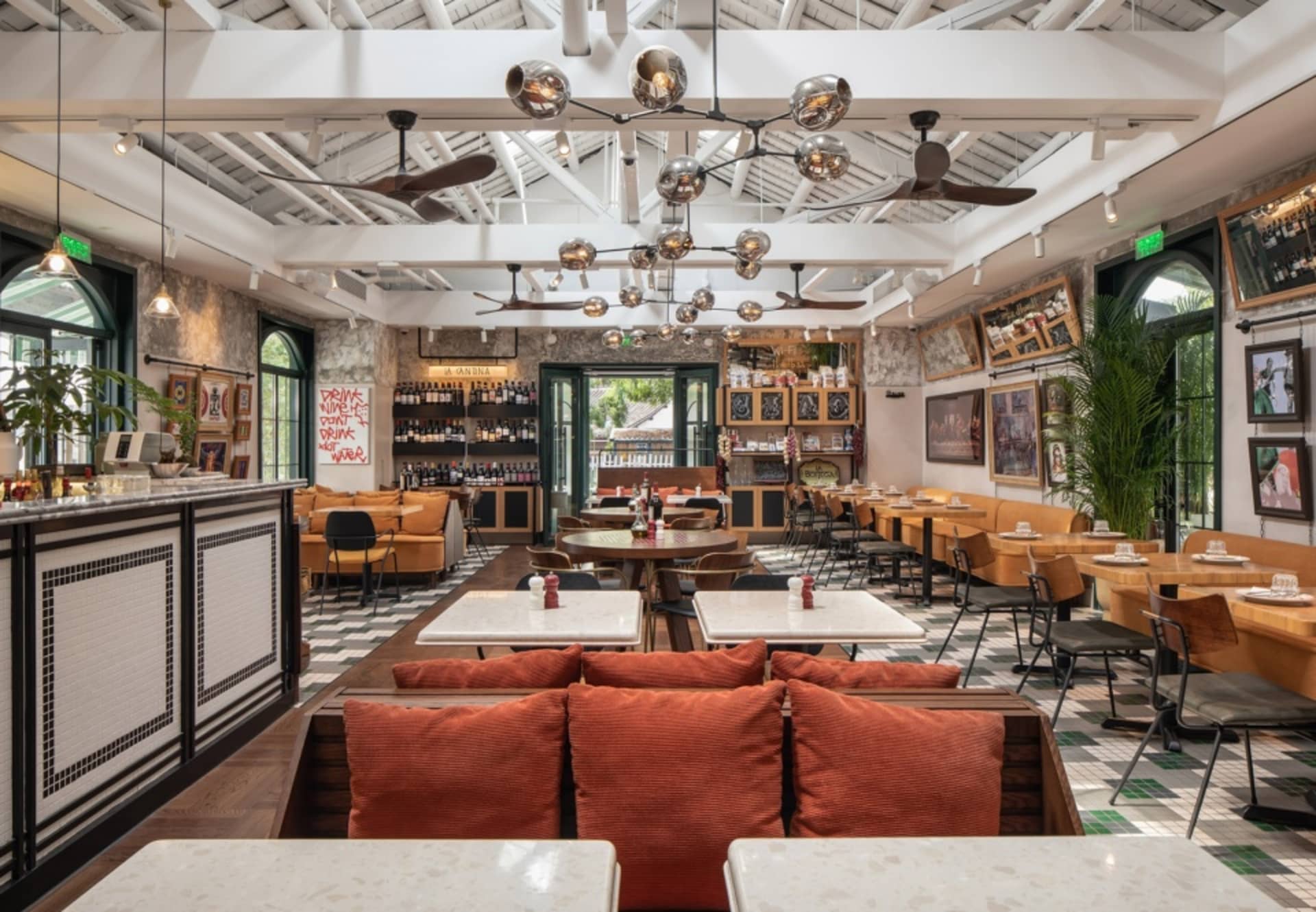 Interior of a cafe bar with wooden furniture, concrete flooring, and indoor plants.