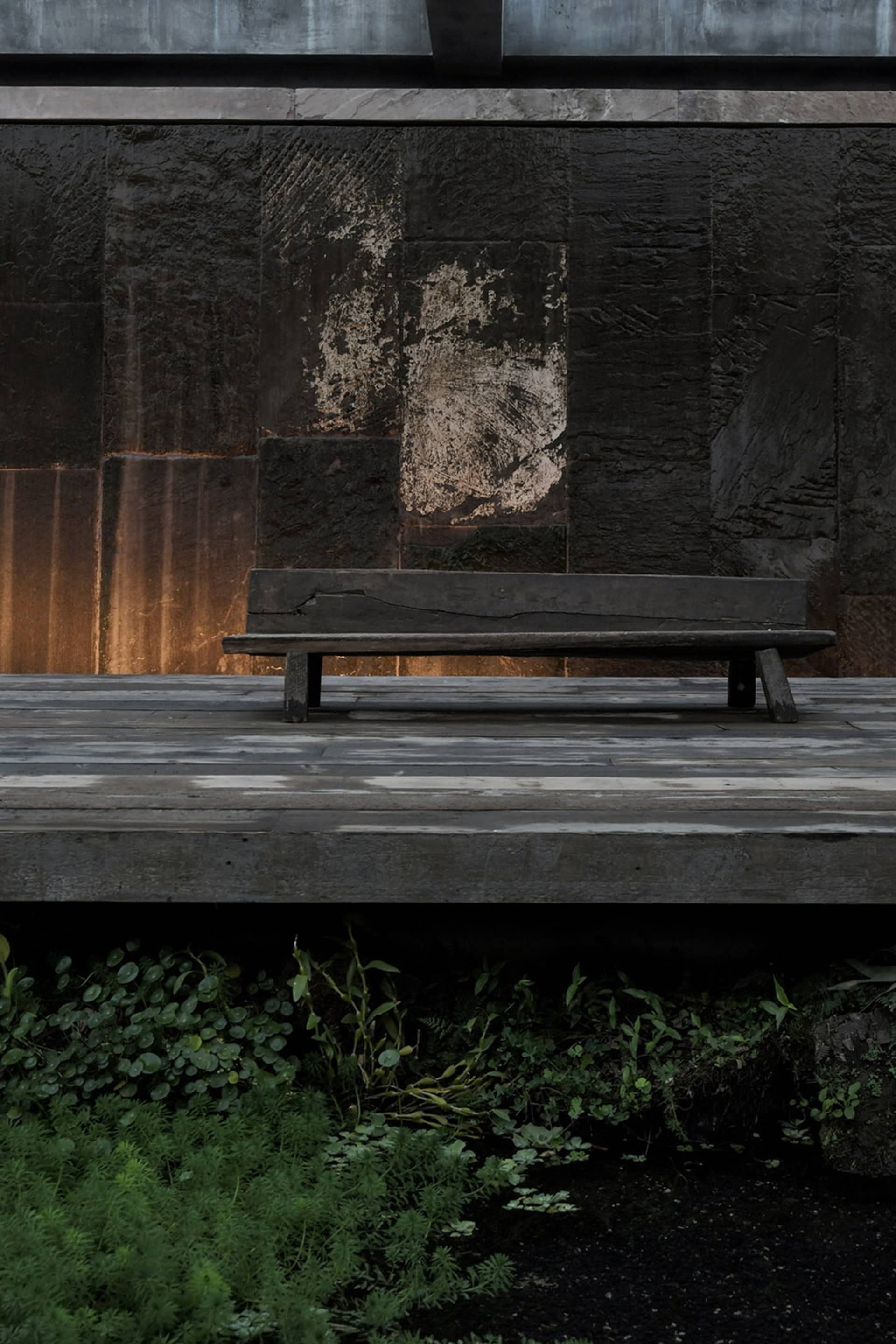 A minimalist park bench made of wood in a parking lot setting.