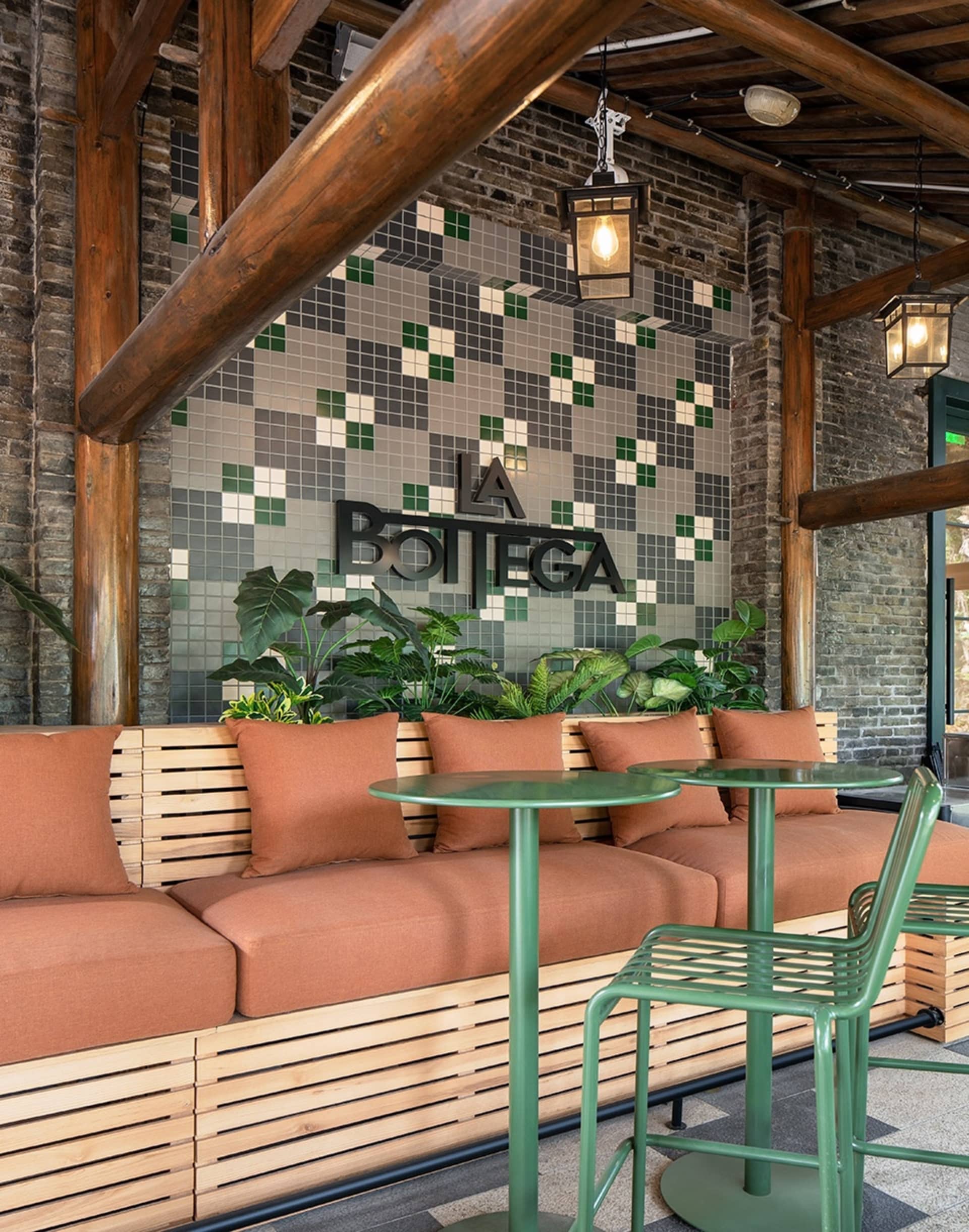 Industrial-style cafe interior with brick walls, tiled mosaic backsplash, wooden seating, and metal furniture.
