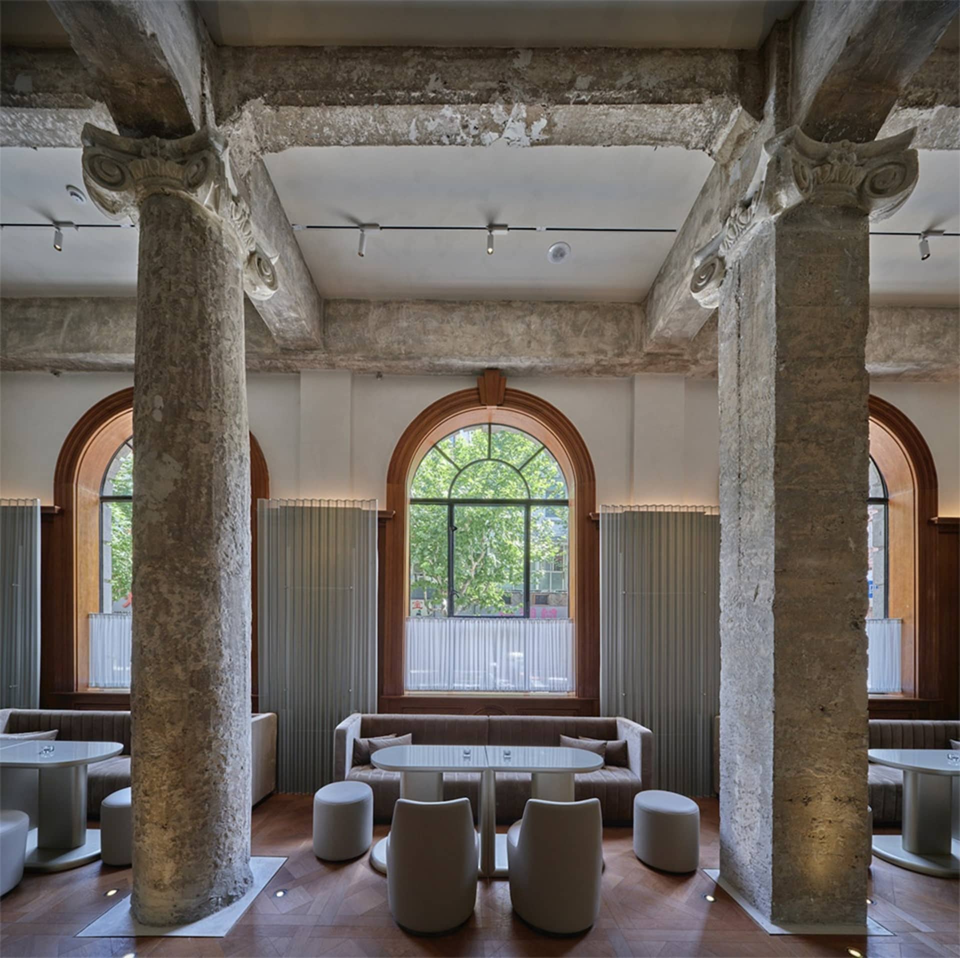 Industrial-style restaurant interior with concrete columns and an arched window.
