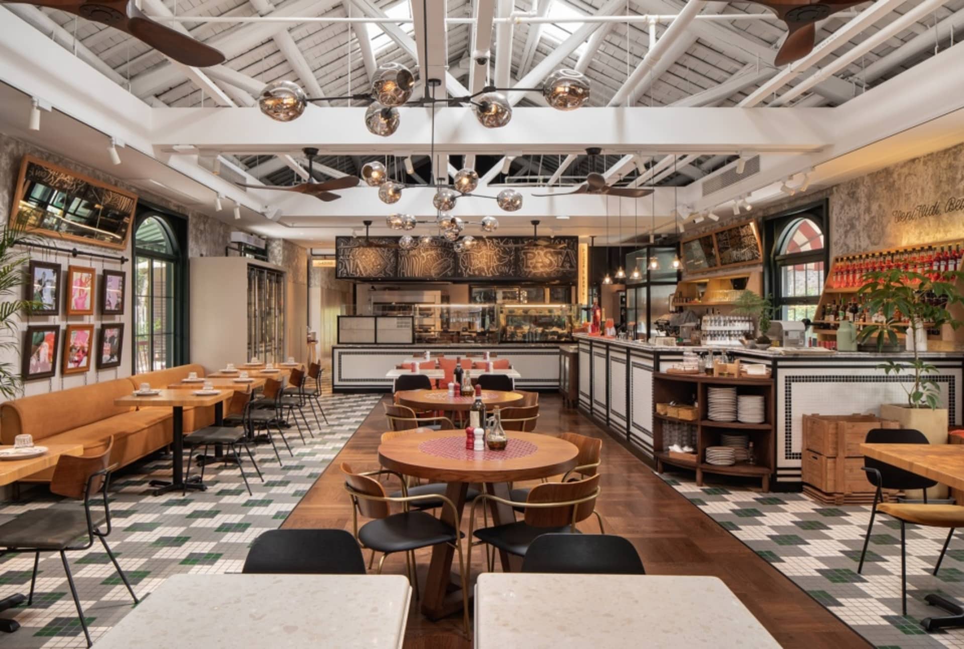 A spacious, industrial-style restaurant with wooden tables, metal chairs, concrete flooring, and ceramic tiles.