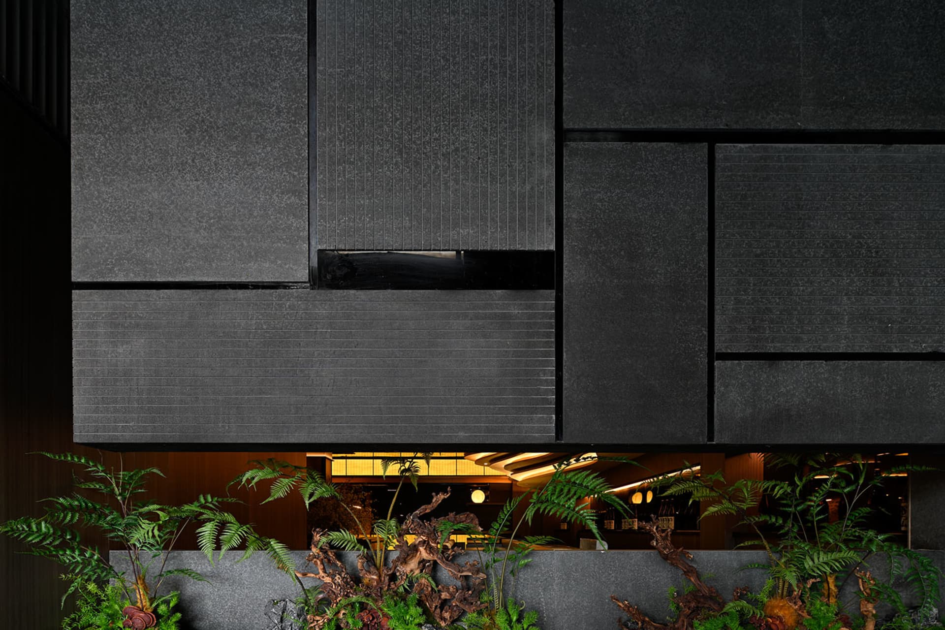 Concrete architecture with indoor plants and black panels.