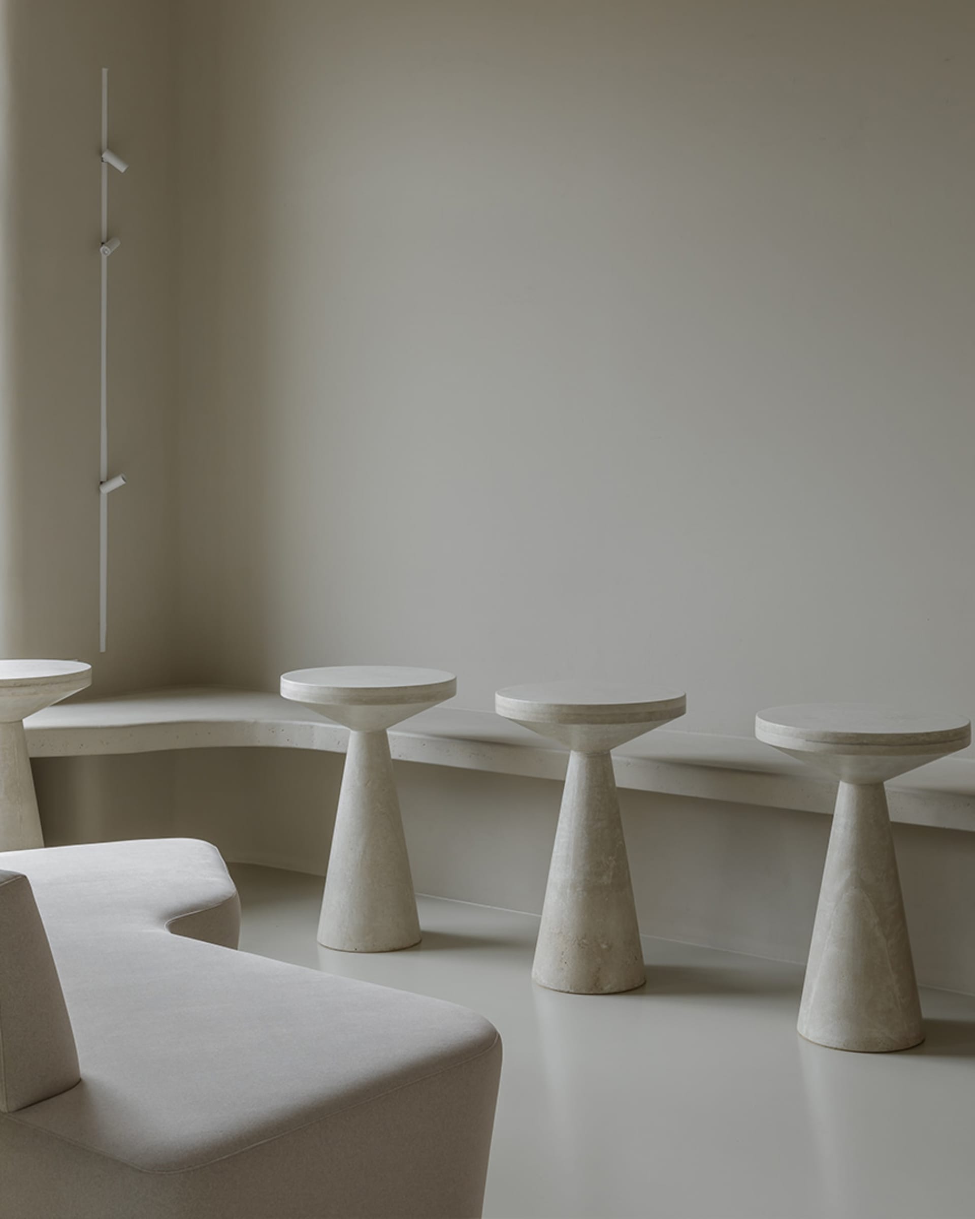 Modern minimalist seating area with concrete and marble furniture in an atrium setting.