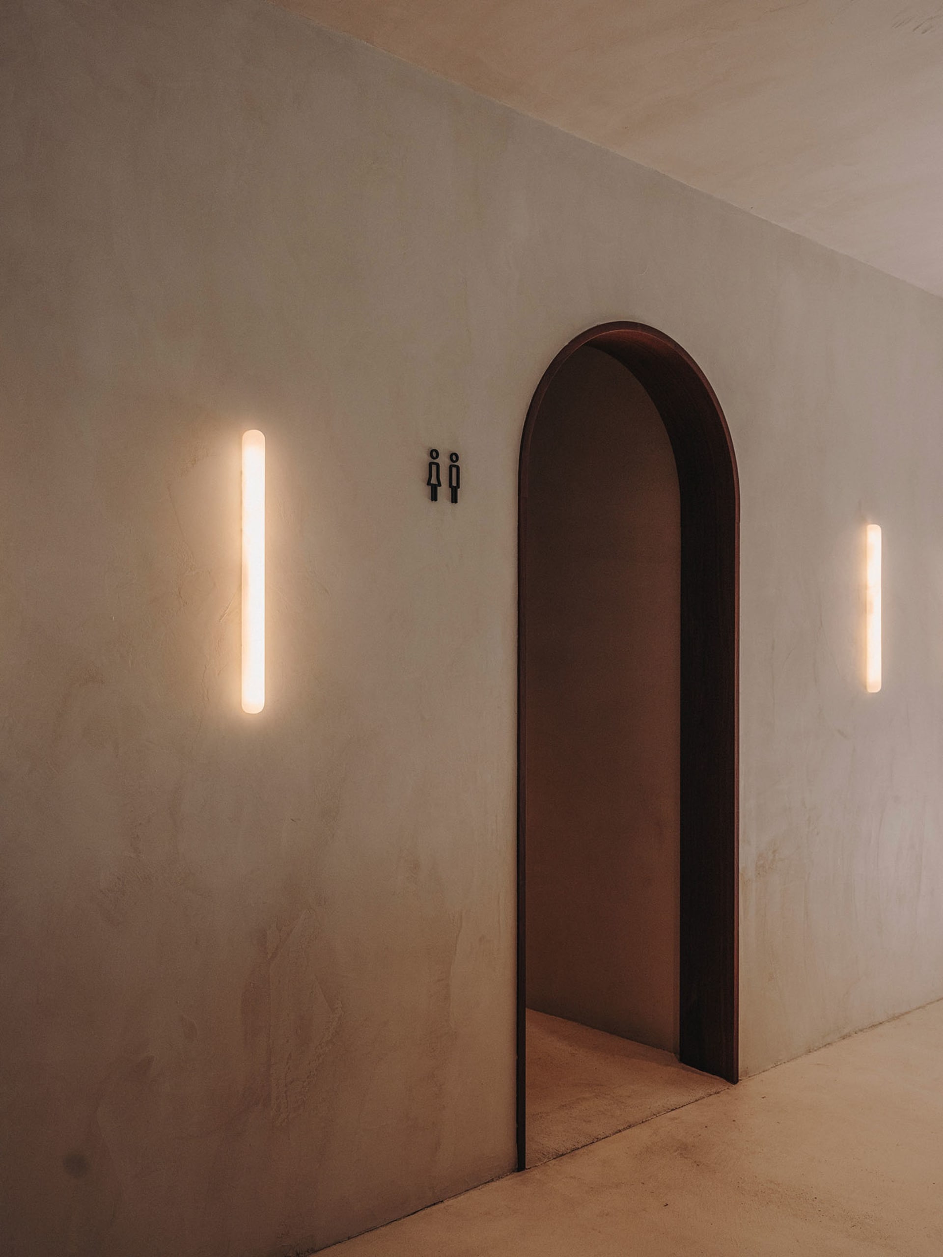 A minimalist entryway featuring a concrete archway with linear lighting fixtures.