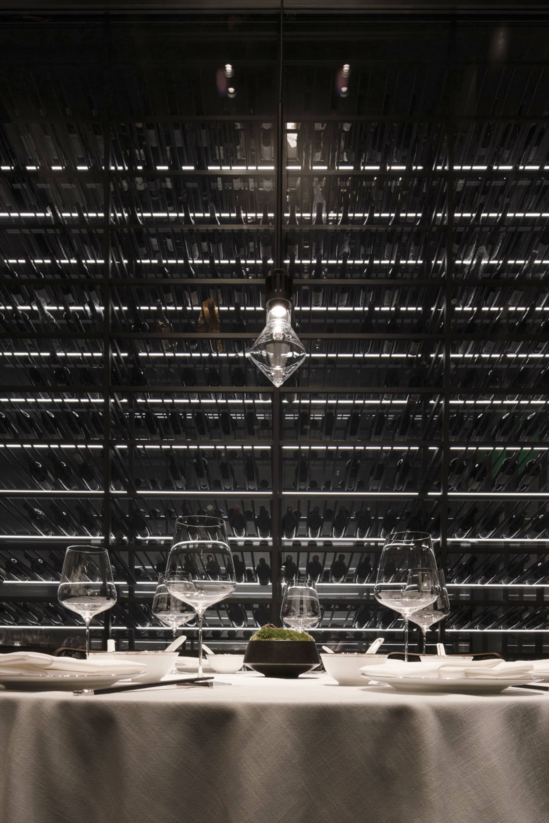 A modern industrial restaurant interior with metal racks, glassware, and minimalist design.