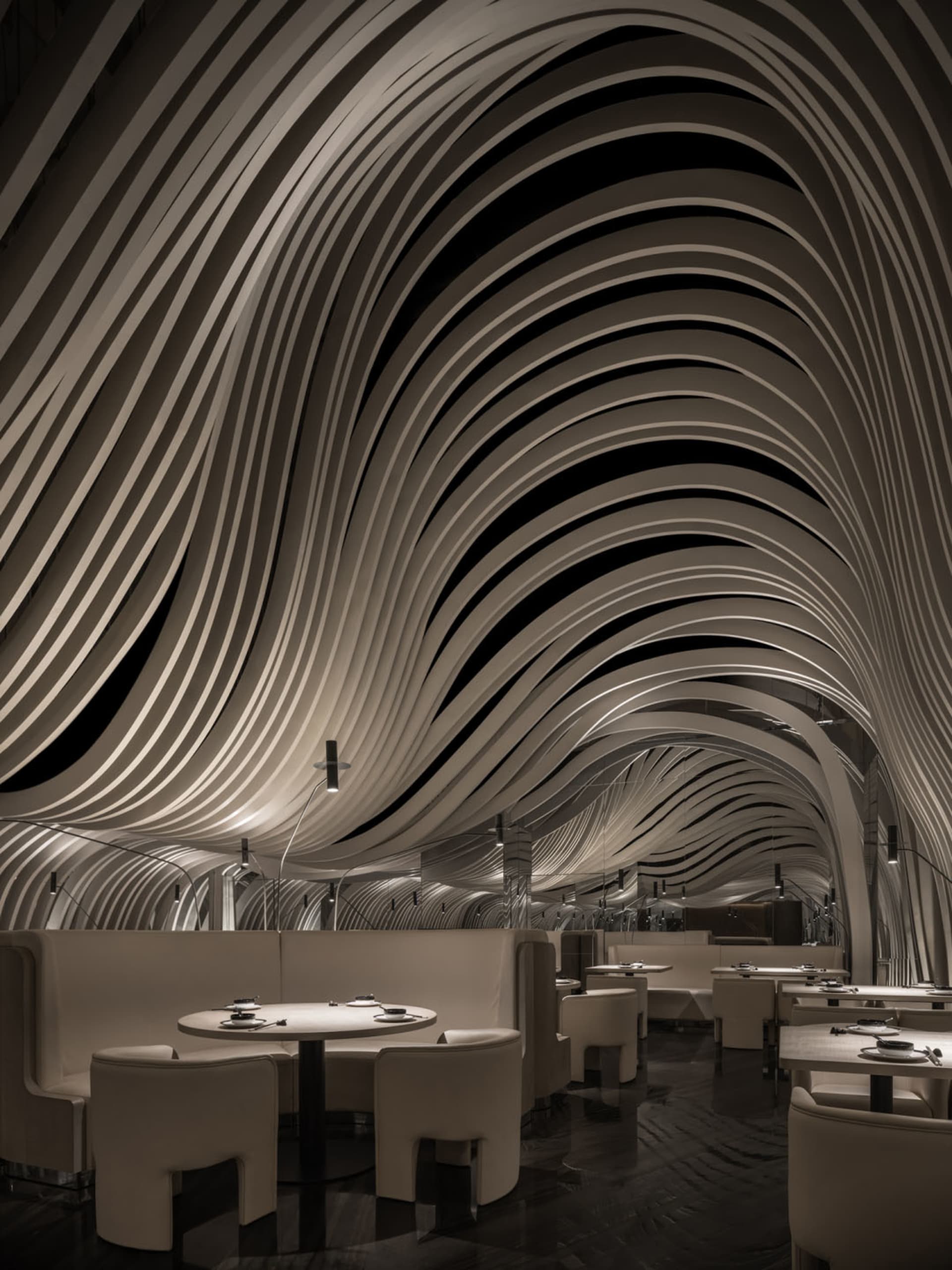 A minimalist white interior with a curved metal roof and illuminated by spotlights.