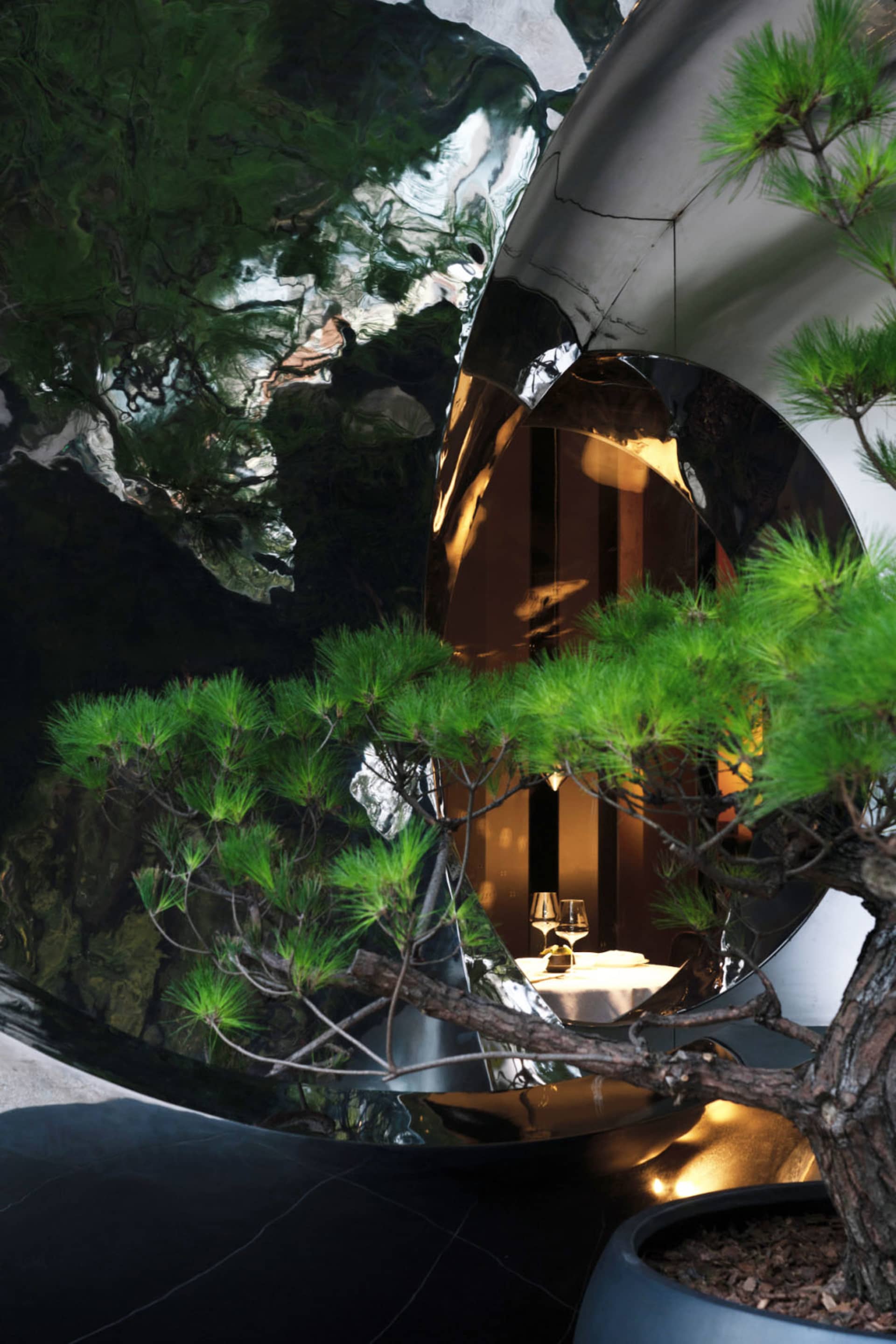 現代餐廳室內擺放圓形鏡面金屬雕塑與盆栽,營造精緻用餐體驗