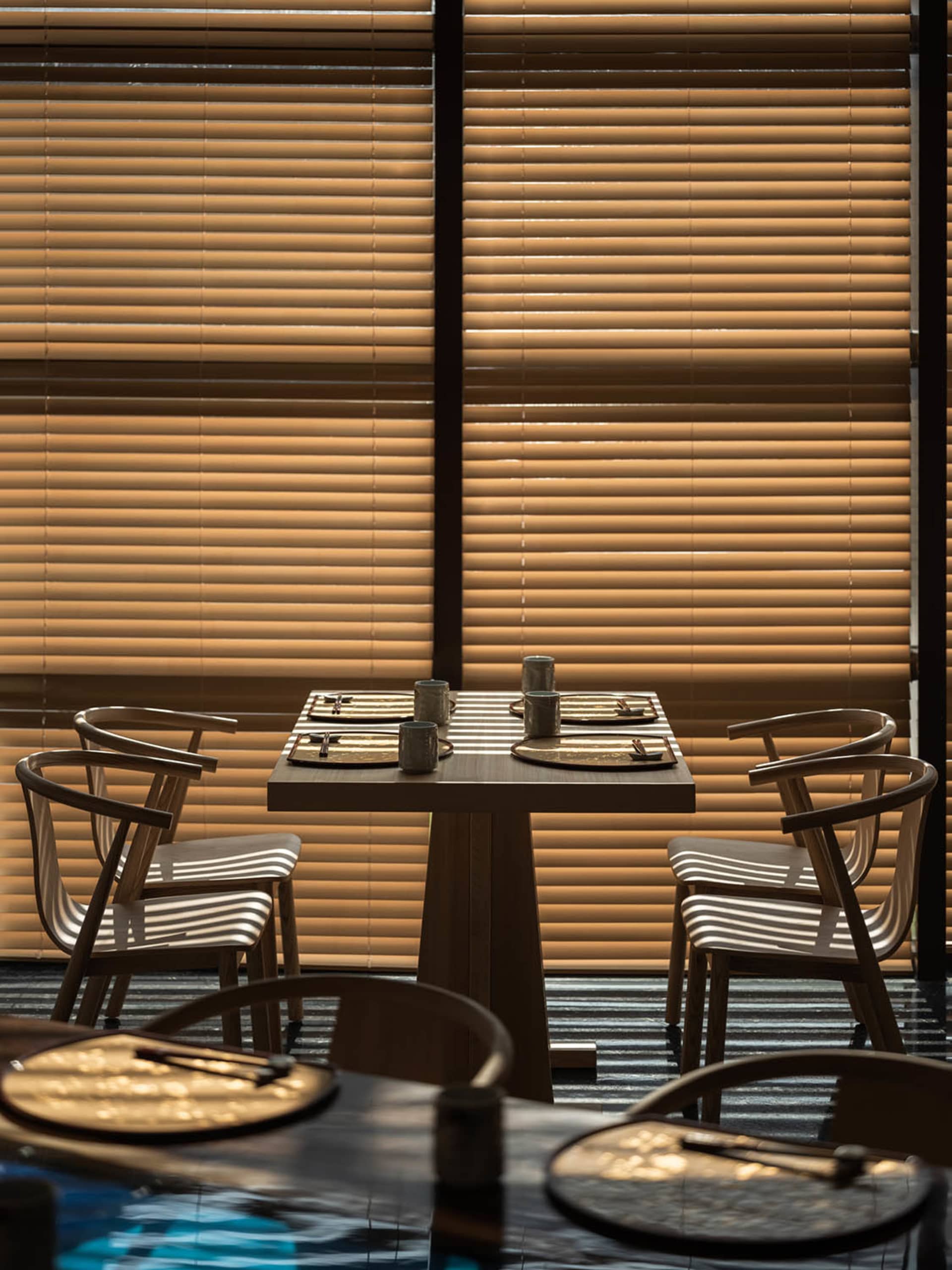A modern restaurant room with wooden furniture and a table setup for dining.