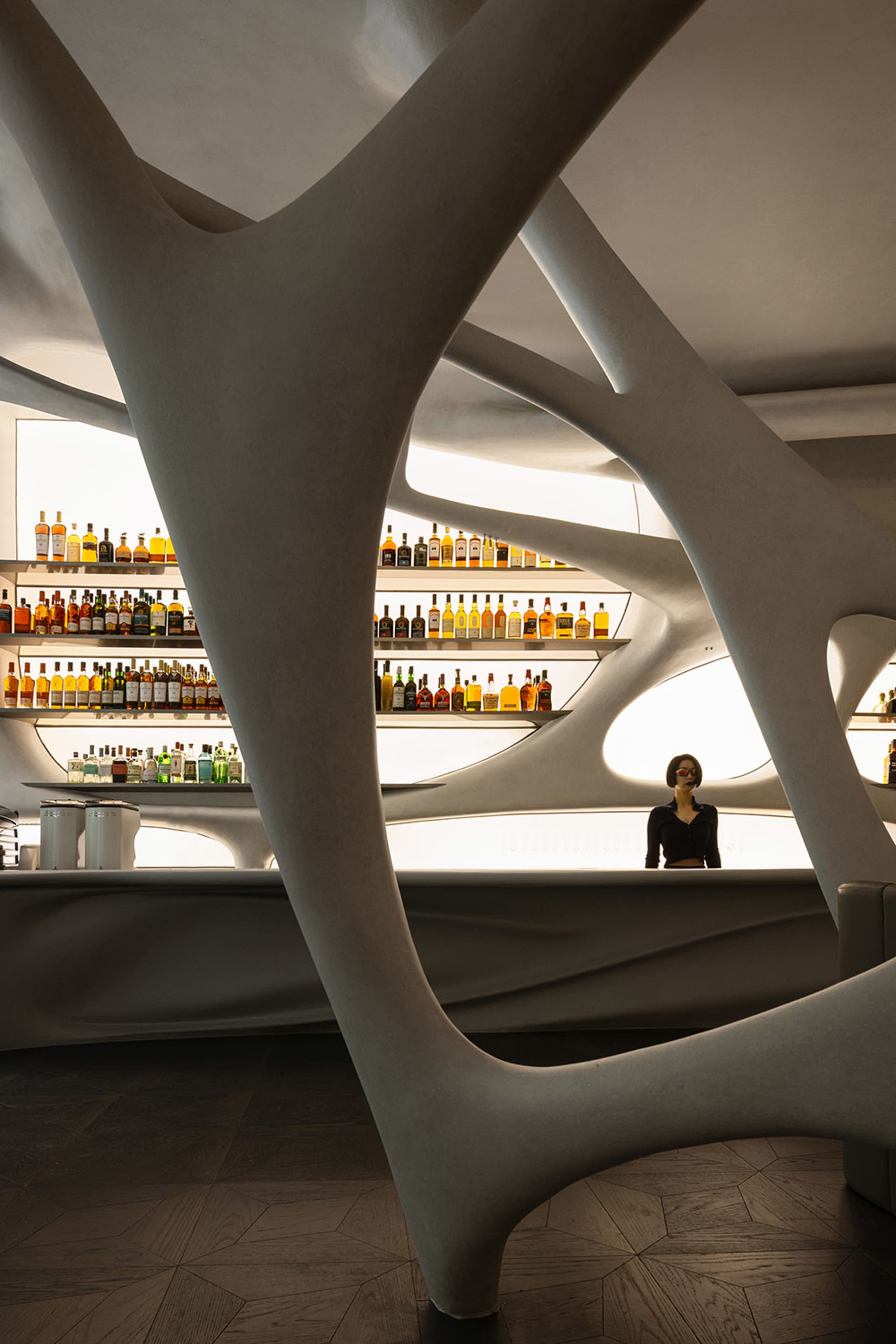 A modern bar interior with a concrete ceiling and wavy, organic architectural design.