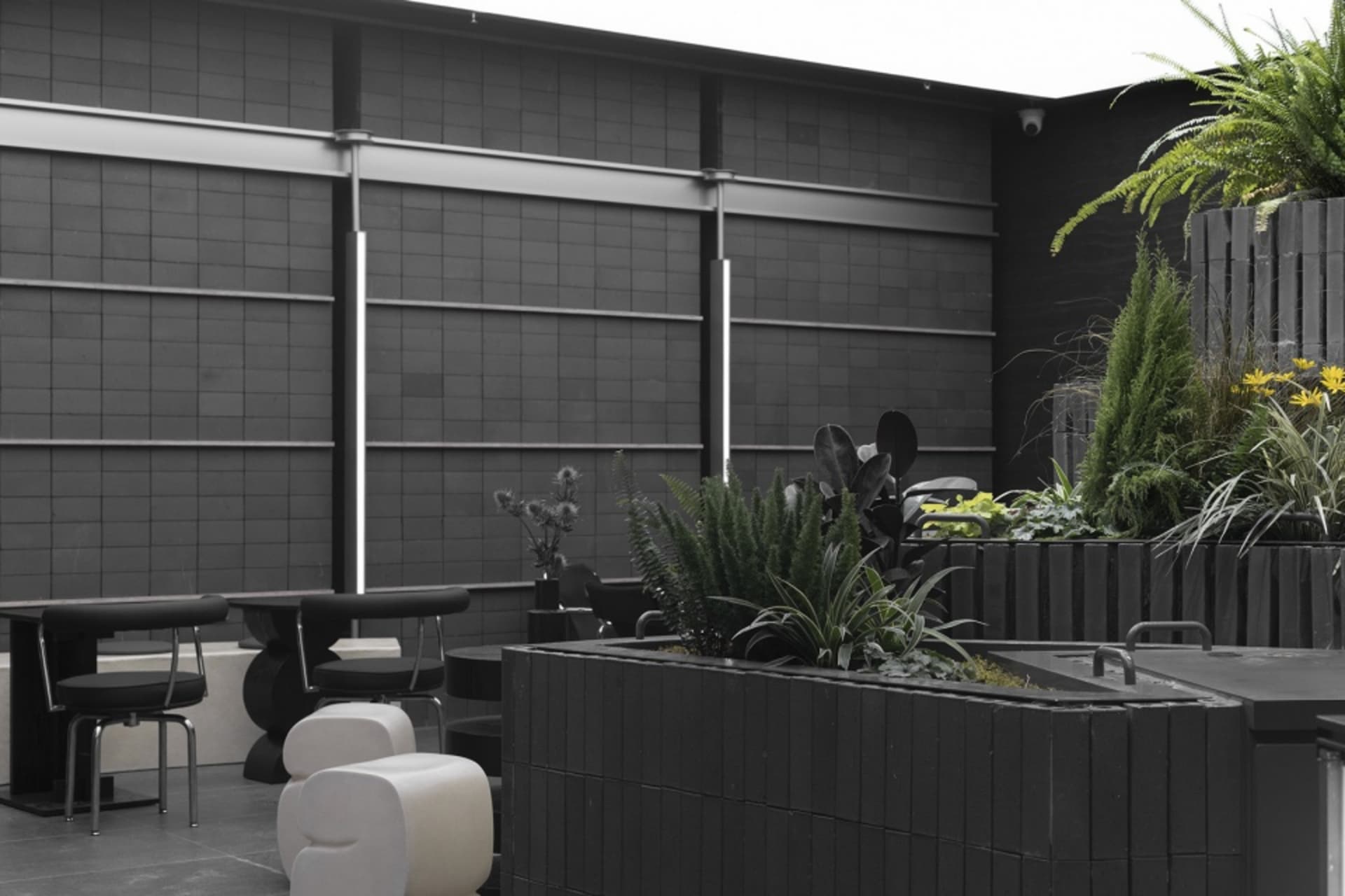 Modern urban lounge area with concrete walls, white furniture, and green plants.